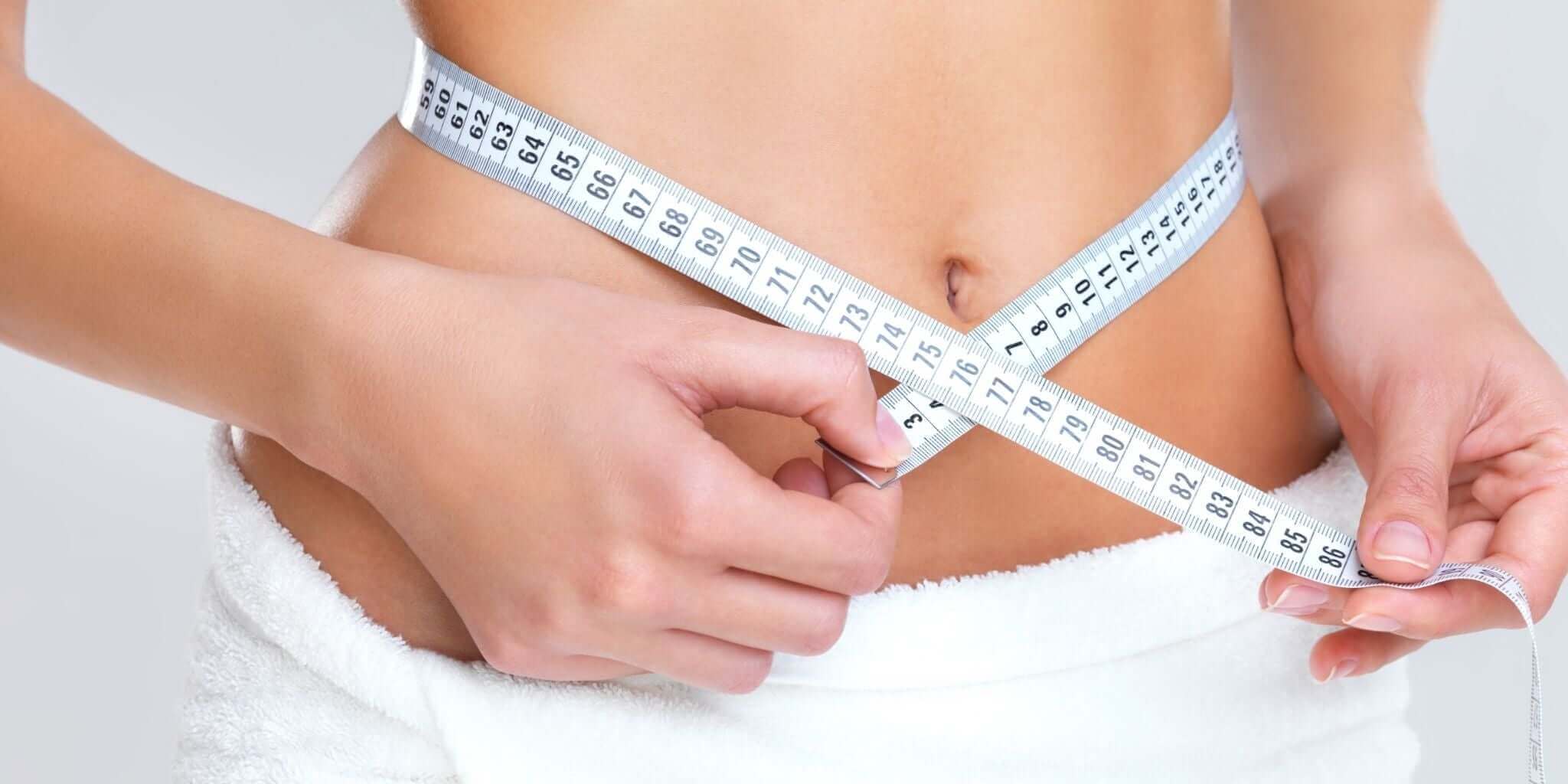 Close-up of a person measuring their waist with a tape measure, symbolizing natural weight management and boosting metabolism. The person’s stomach is visible, suggesting health, wellness, and reducing cravings naturally.