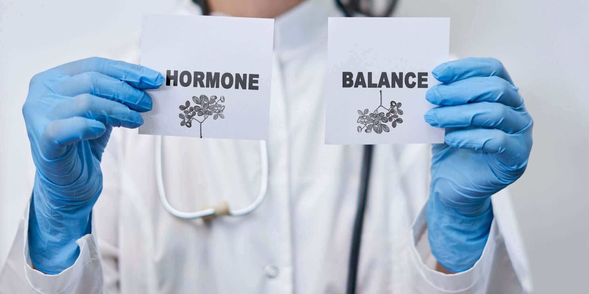 Doctor holding cards with the words 'Hormone' and 'Balance,' symbolizing natural hormone regulation through Sacred Plant Co’s herbal remedies.