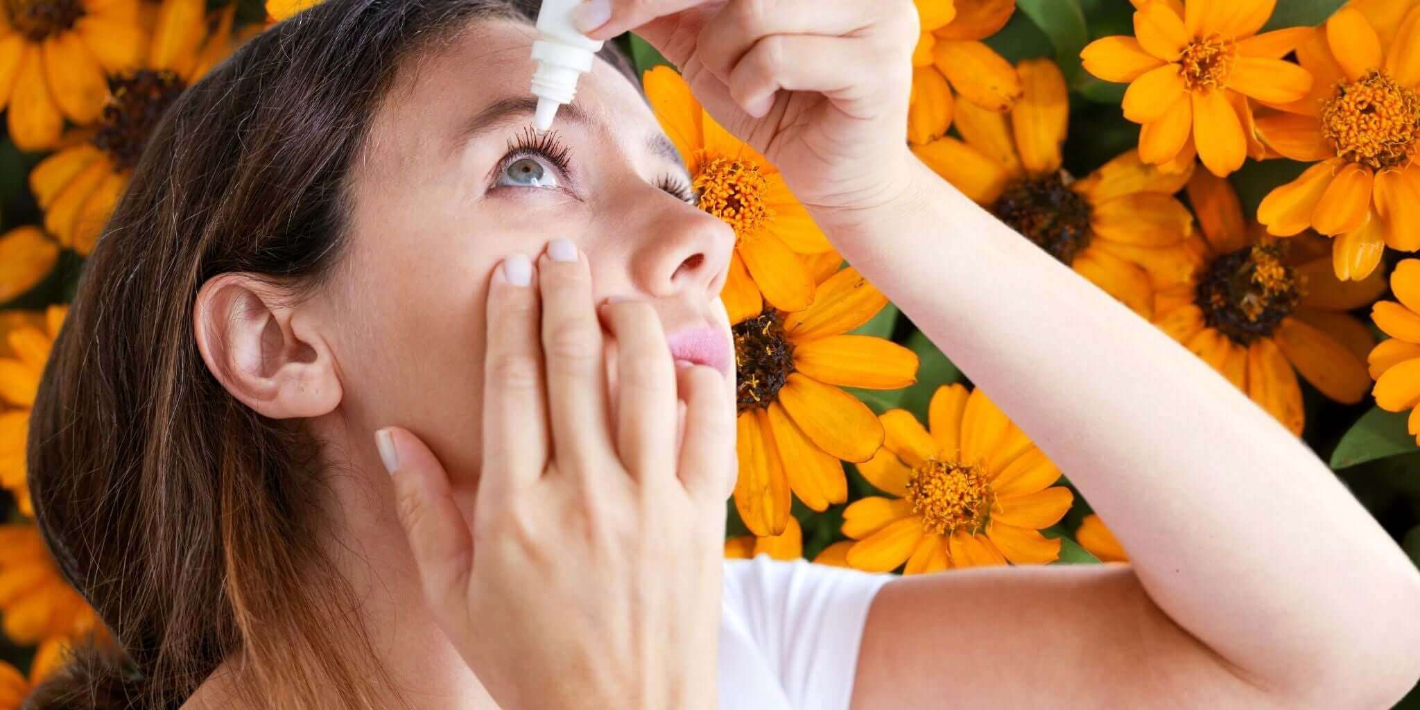 A woman using eye drops, symbolizing care and relief for vision health, set against a vibrant backdrop of blooming orange flowers.