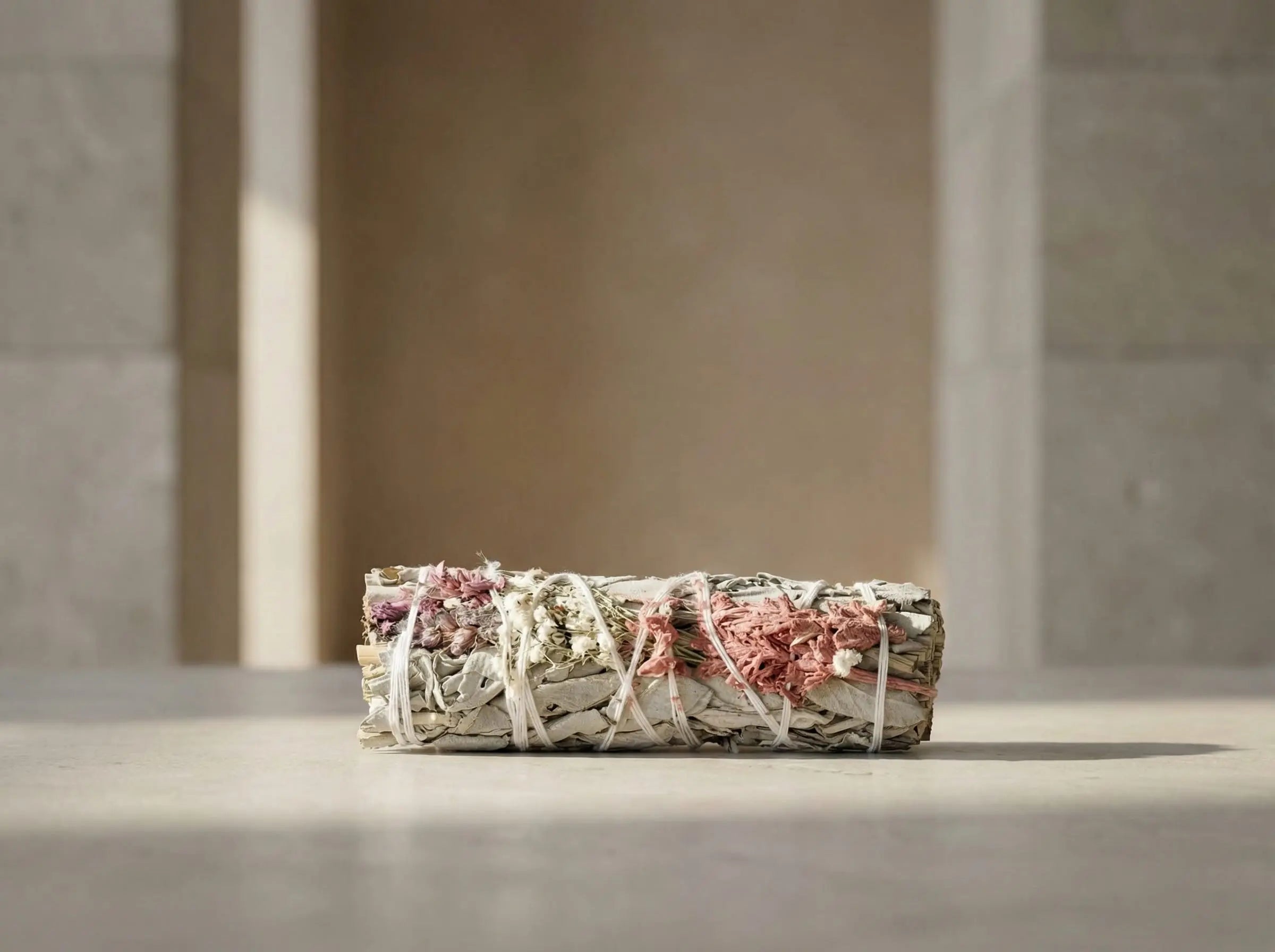 Consecrated 4-inch white sage smudge stick, hand-tied and air-dried, photographed in a minimalist setting.