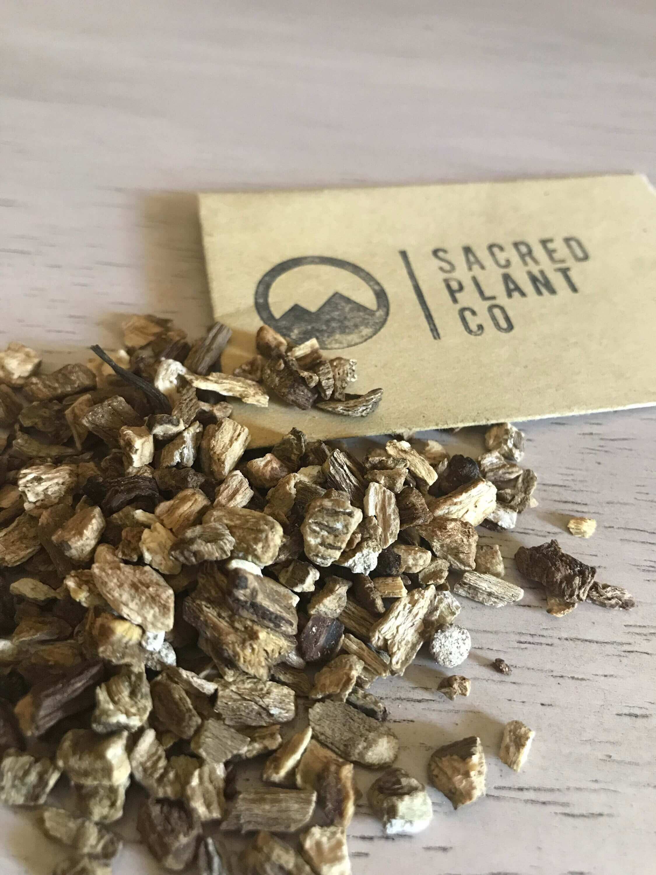Premium Burdock Root scattered beside Sacred Plant Co label, angled to highlight the superior herb quality.