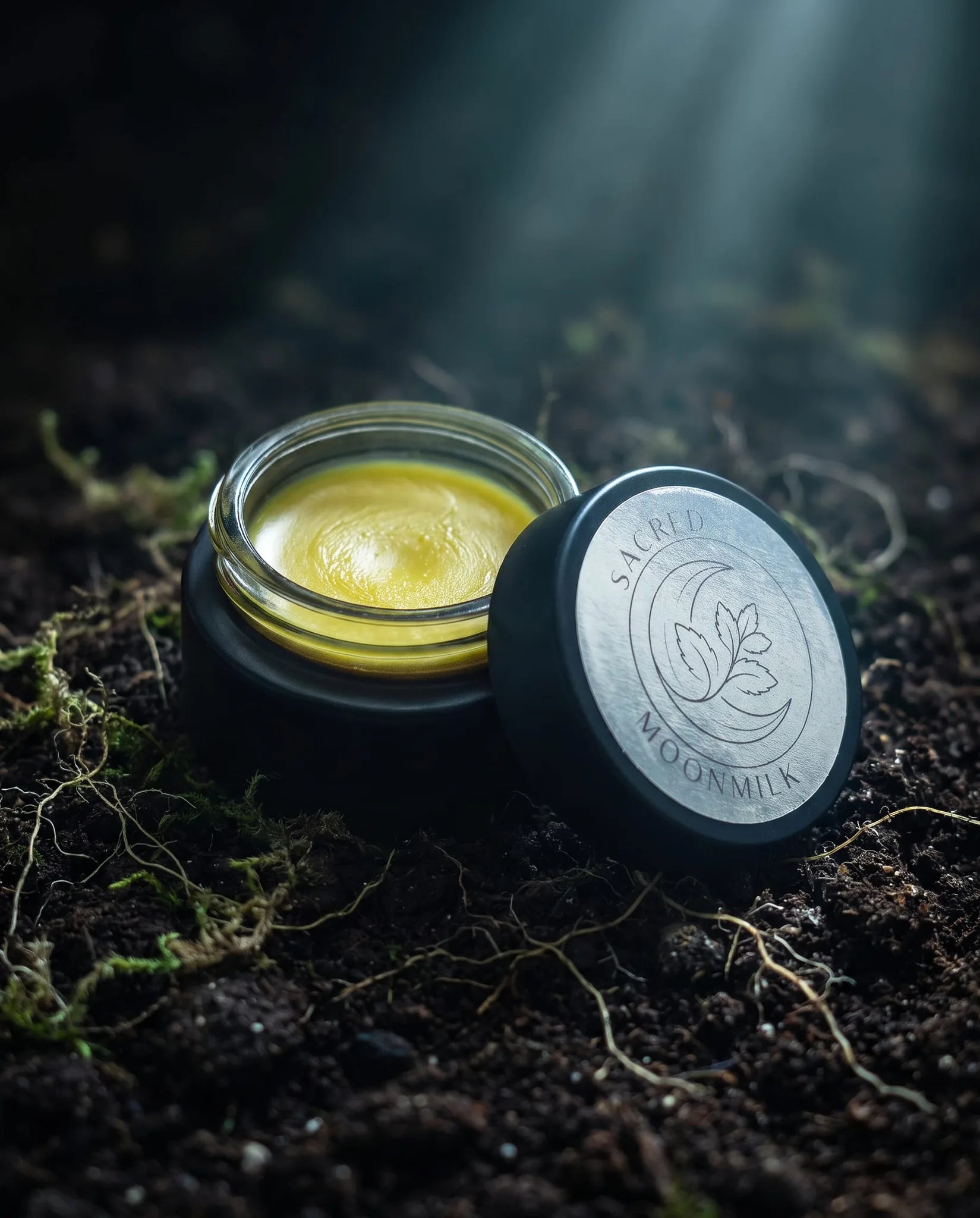 Moonmilk mugwort night balm styled on a dark moody surface for an evening skincare and wind-down ritual