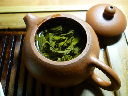 teeped loose leaf green tea in a traditional clay teapot, showcasing the vibrant green leaves of high-quality Sencha ready for a perfect brew.