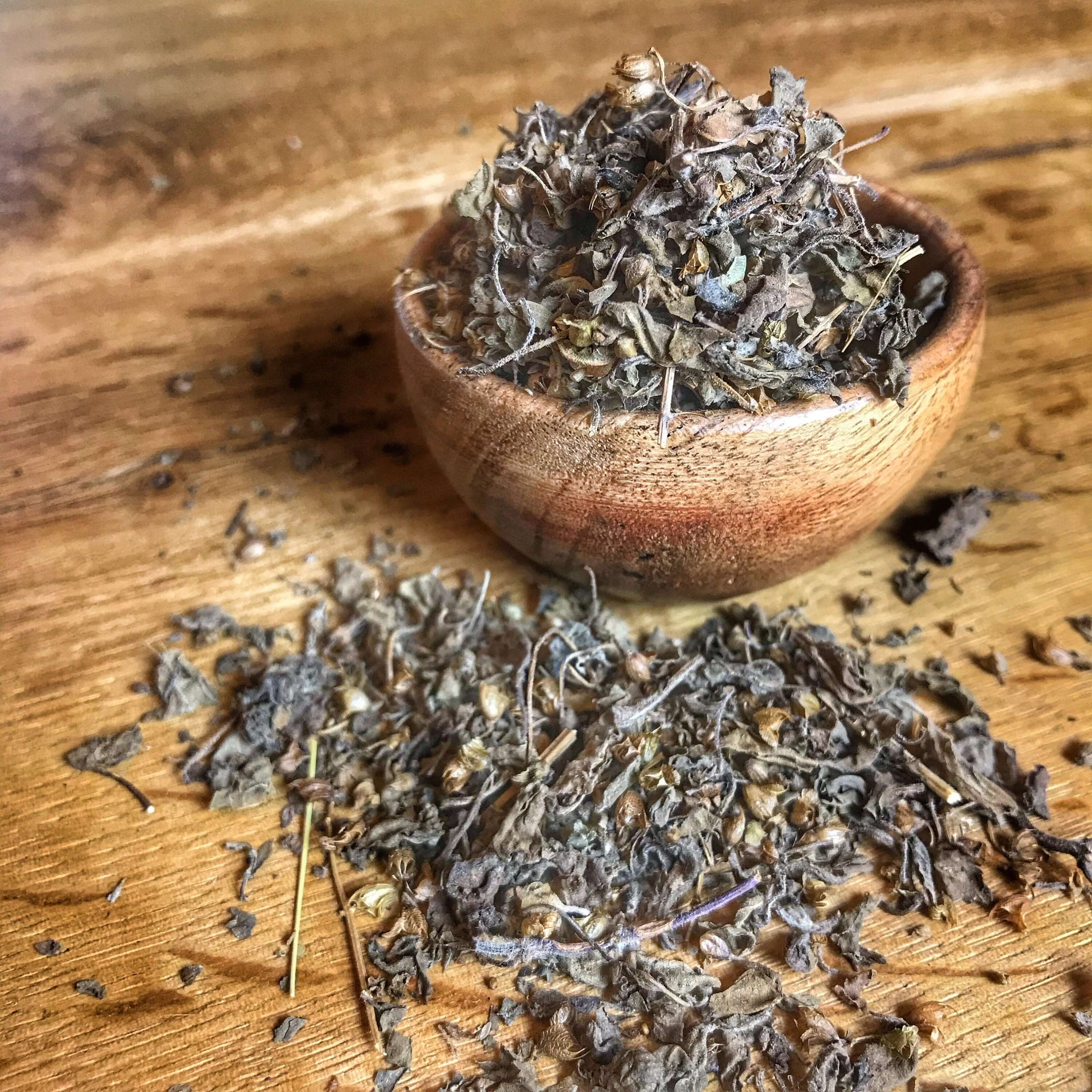 Premium Sacred Plant Co dried Tulsi Herb in a wooden bowl, beautifully arranged with scattered leaves on a rustic background.