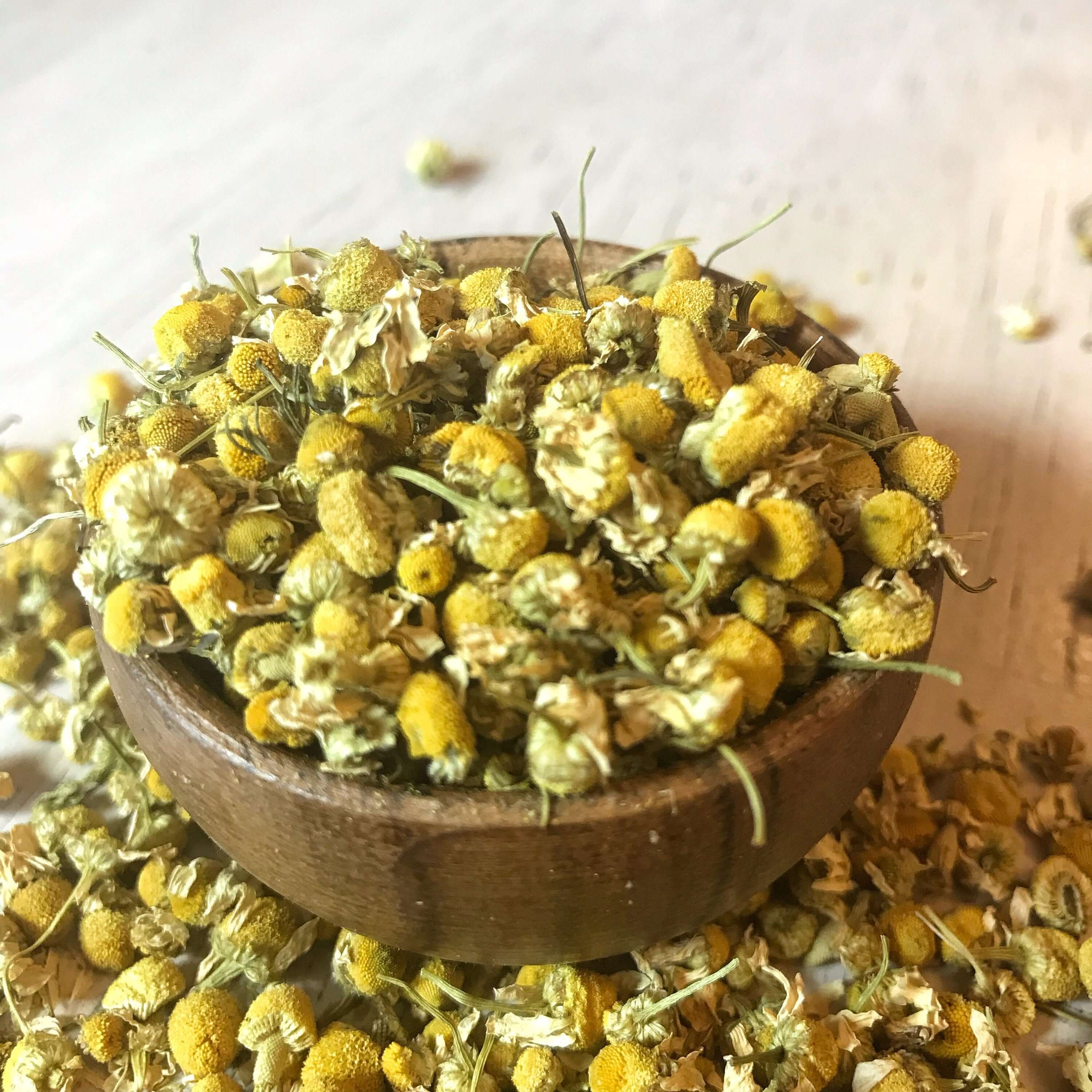 Premium dried Chamomile Flowers from Sacred Plant Co, displayed in a wooden bowl, emphasizing natural wellness.