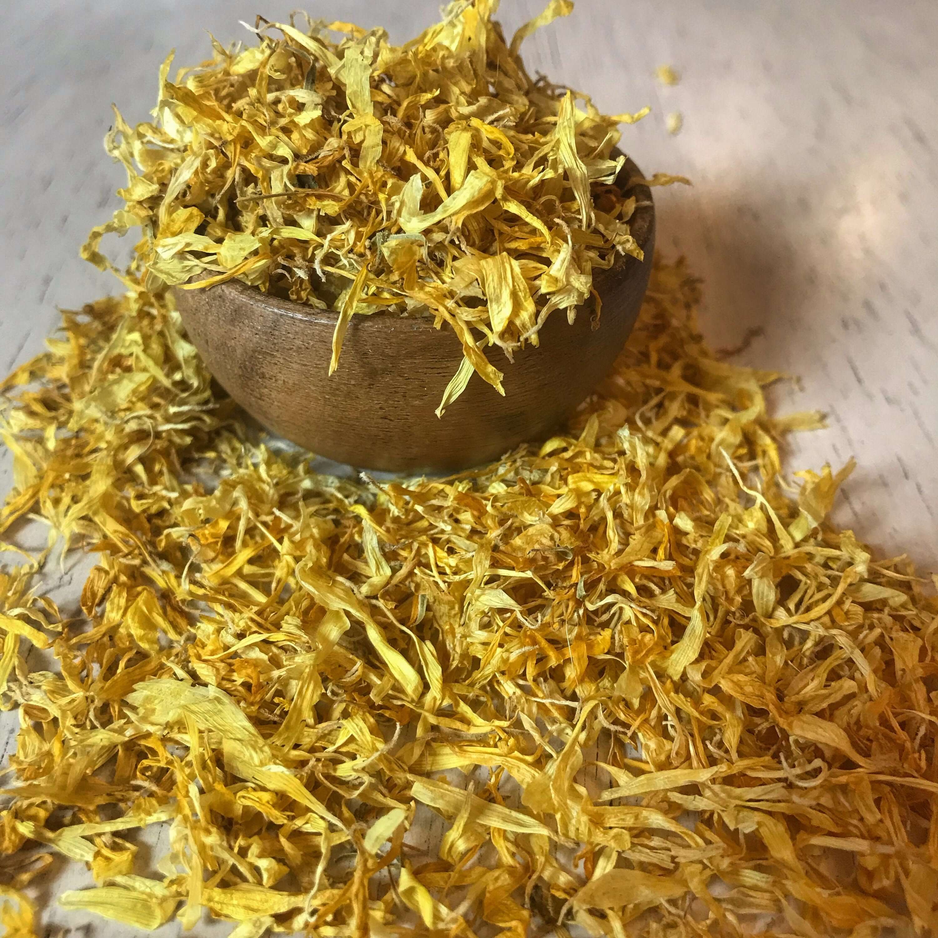 A rich pile of Sacred Plant Co dried Calendula Petals, glowing under soft natural light, highlighting their fine texture and vivid color.