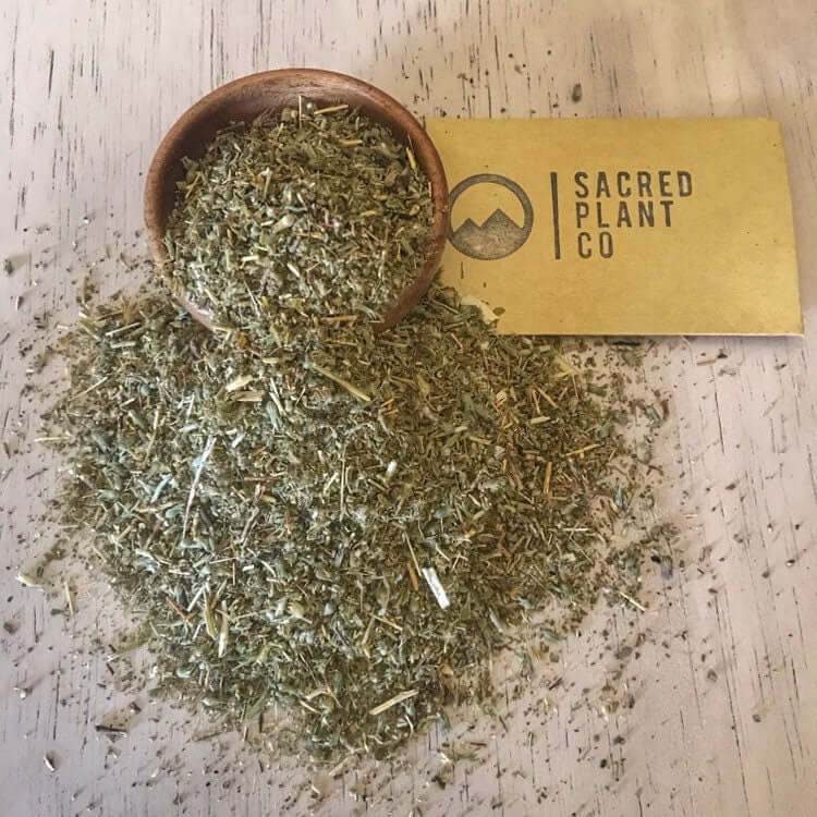 Close-up of high-quality Damiana Herb with Sacred Plant Co branding, spread across a textured, light wood background.