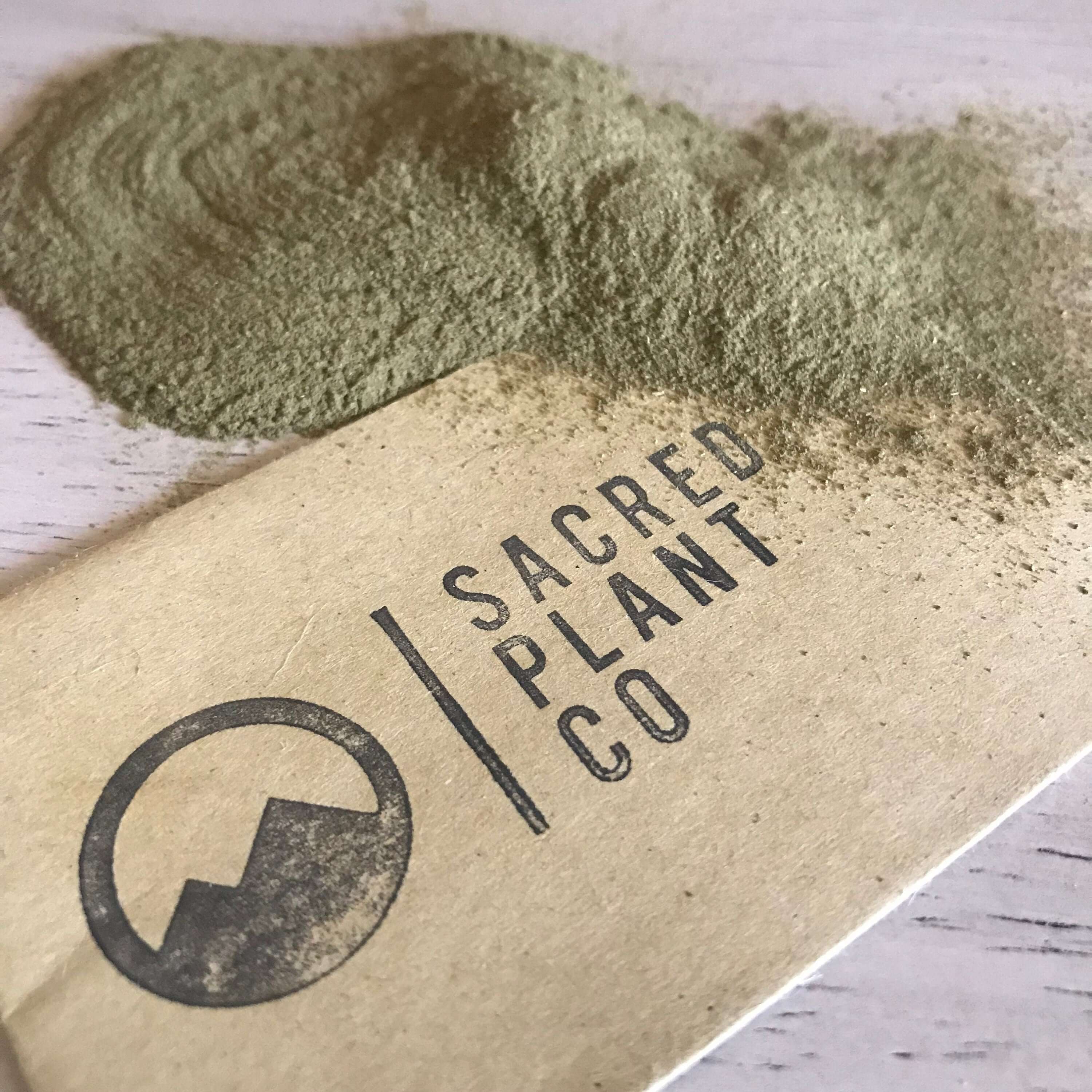 Premium quality Neem Leaf Powder from Sacred Plant Co, with smooth, finely ground texture, green color, and branded kraft paper on light surface.