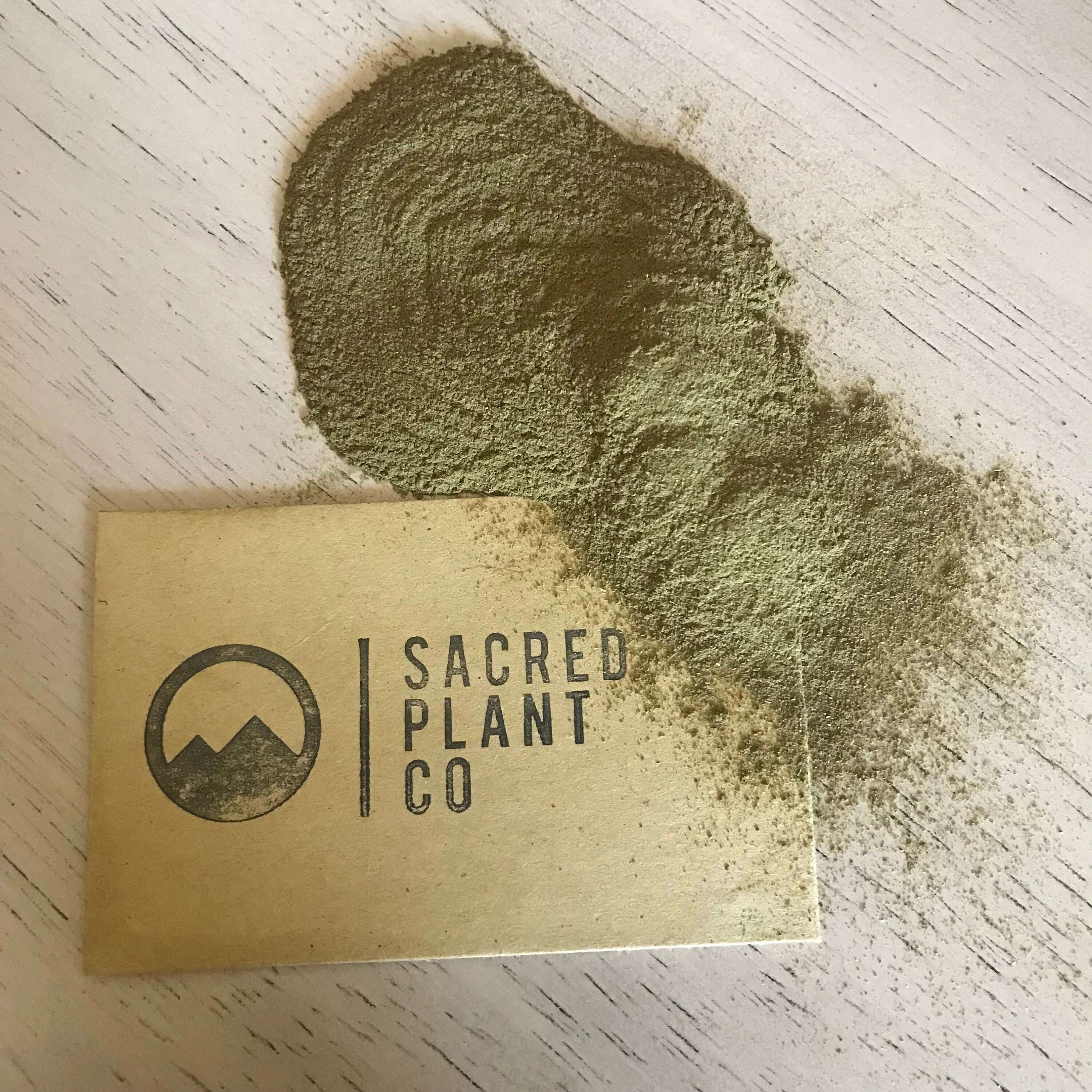 Close-up of finely ground Neem Leaf Powder from Sacred Plant Co, displaying a rich green texture with brand logo in the background.