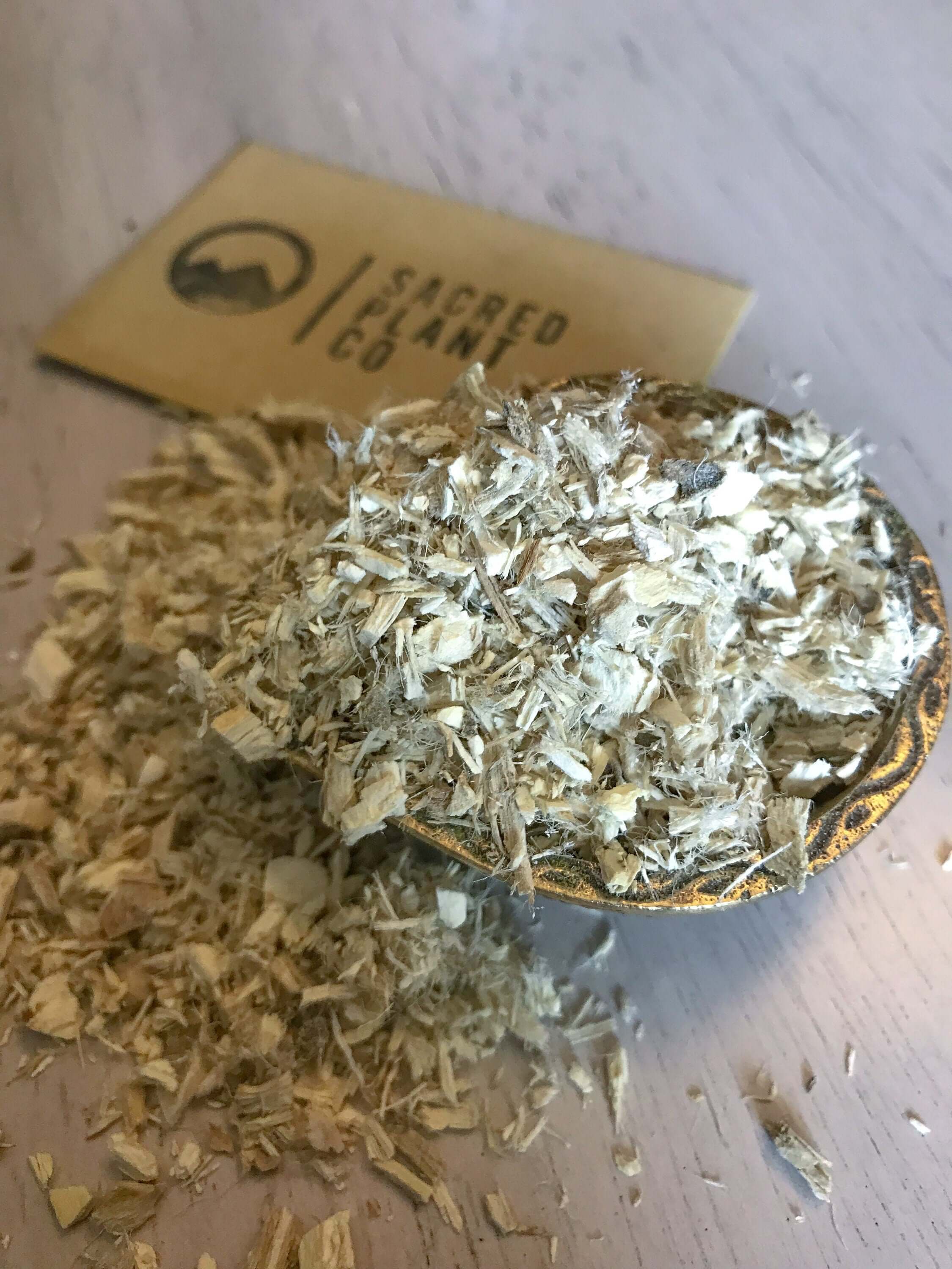 Extracted premium cut of Marshmallow Root, showcasing its fibrous texture and golden color, with Sacred Plant Co branding in the background.