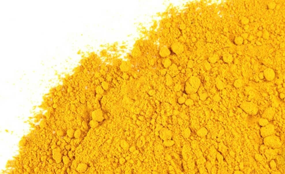 Freshly ground Turmeric Powder, bright golden yellow and rich in antioxidants with a white flat surface, from Sacred Plant Co’s organic herb line.