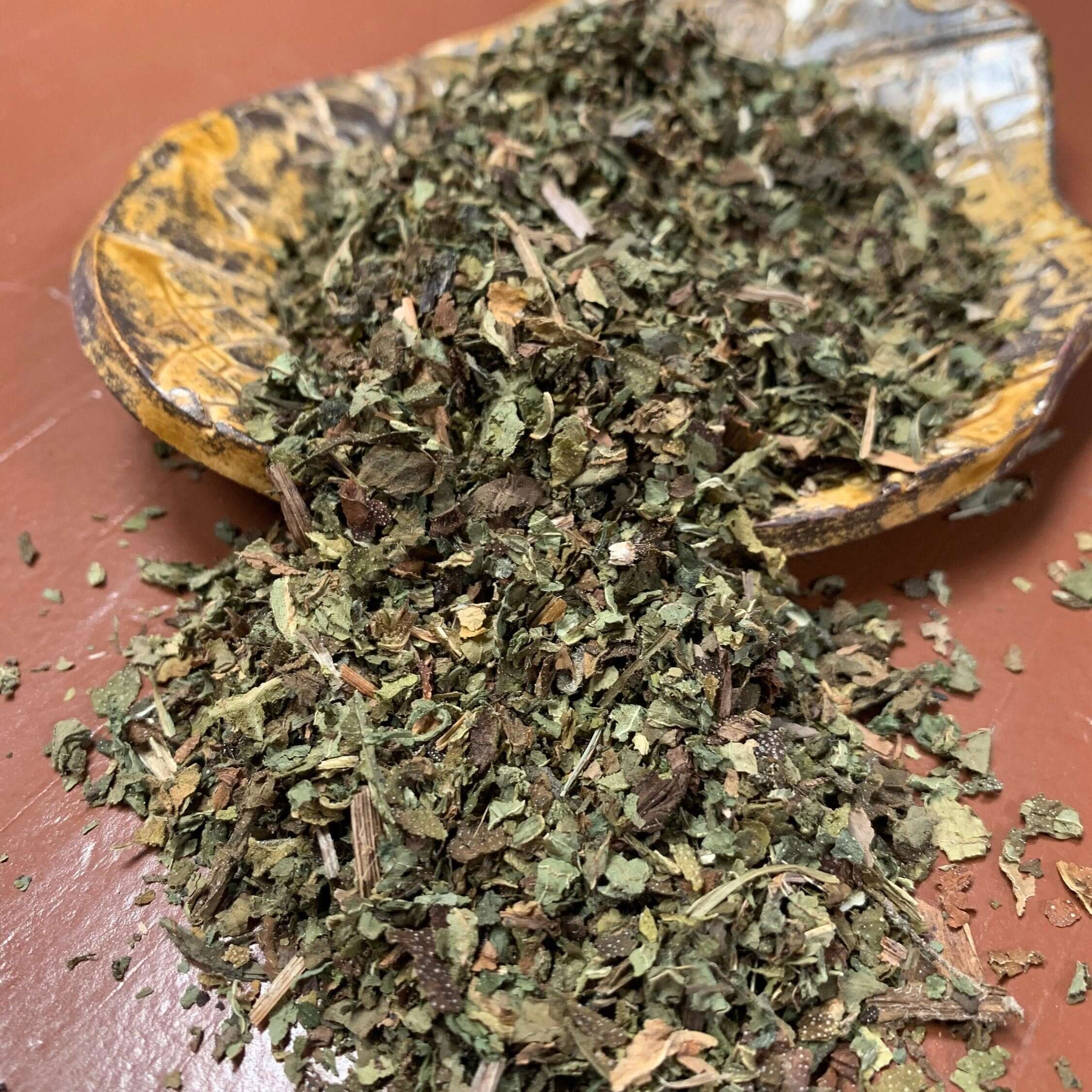 High-quality dried Comfrey Leaf herbal blend from Sacred Plant Co, displayed on a handcrafted dish. Rich green texture for premium wellness.
