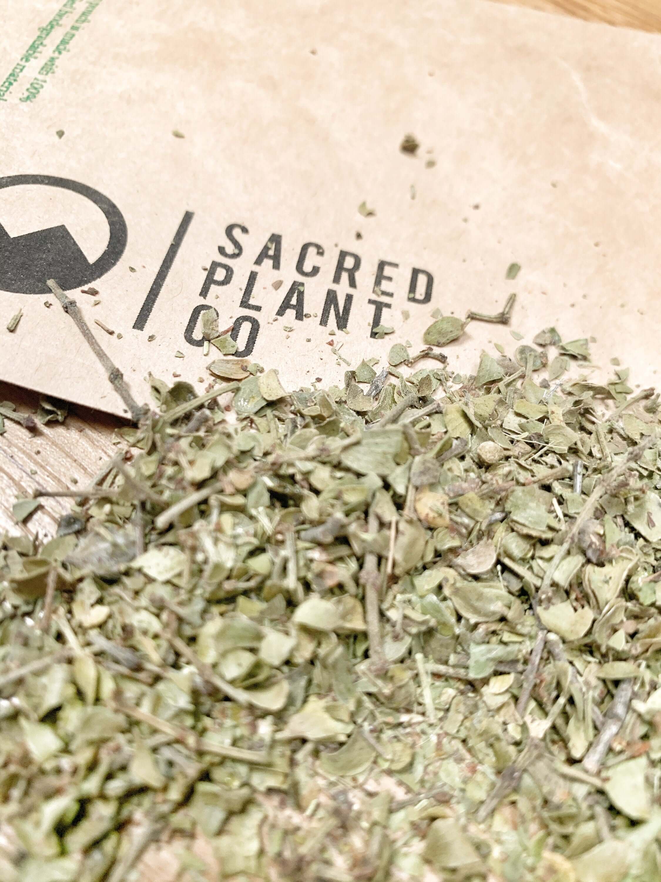 Loose Chaparral Leaf, finely textured herbs scattered on kraft paper packaging from Sacred Plant Co, highlighting premium, organic quality.