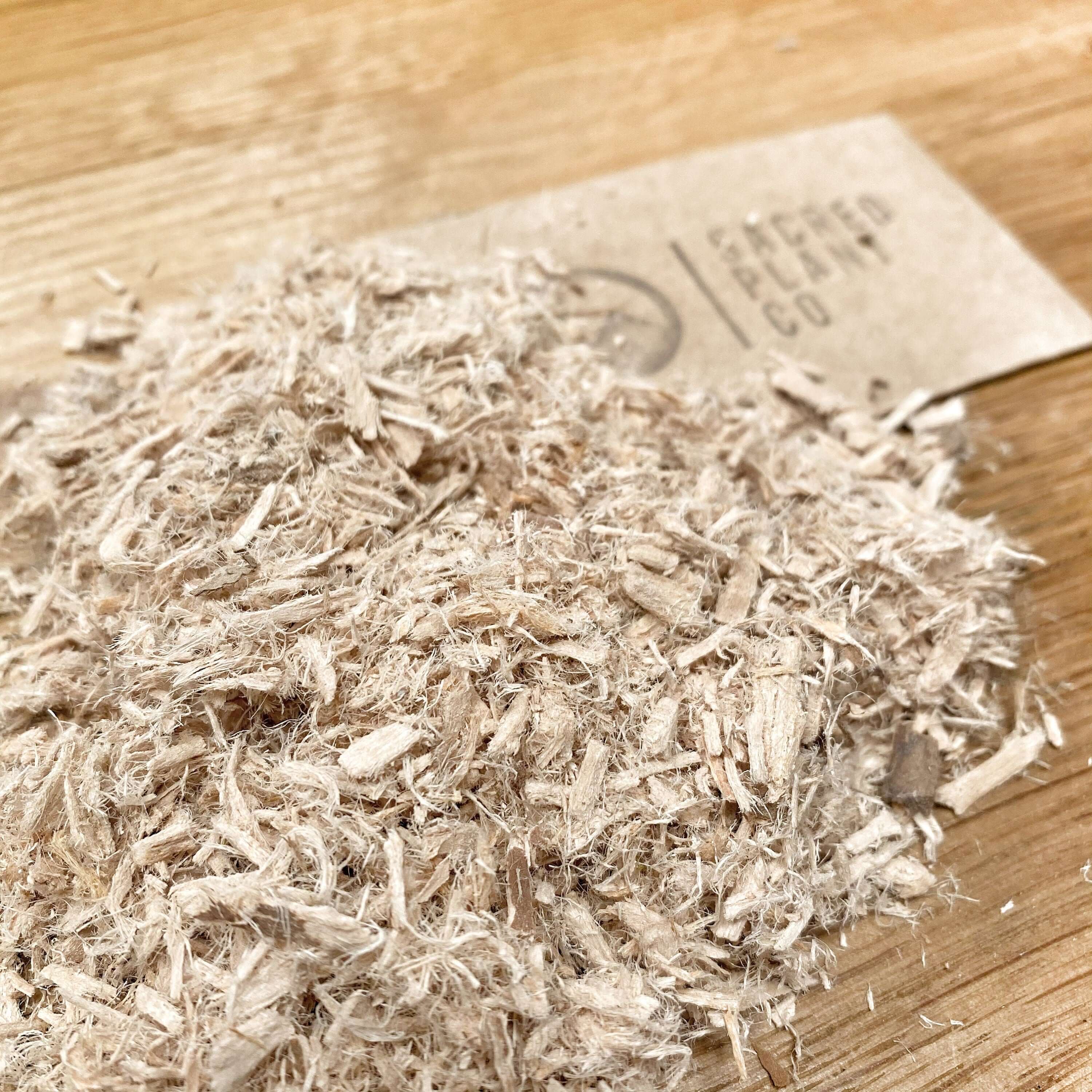 High-quality Slippery Elm Bark from Sacred Plant Co, finely shredded with a beige color, placed on a wooden background.