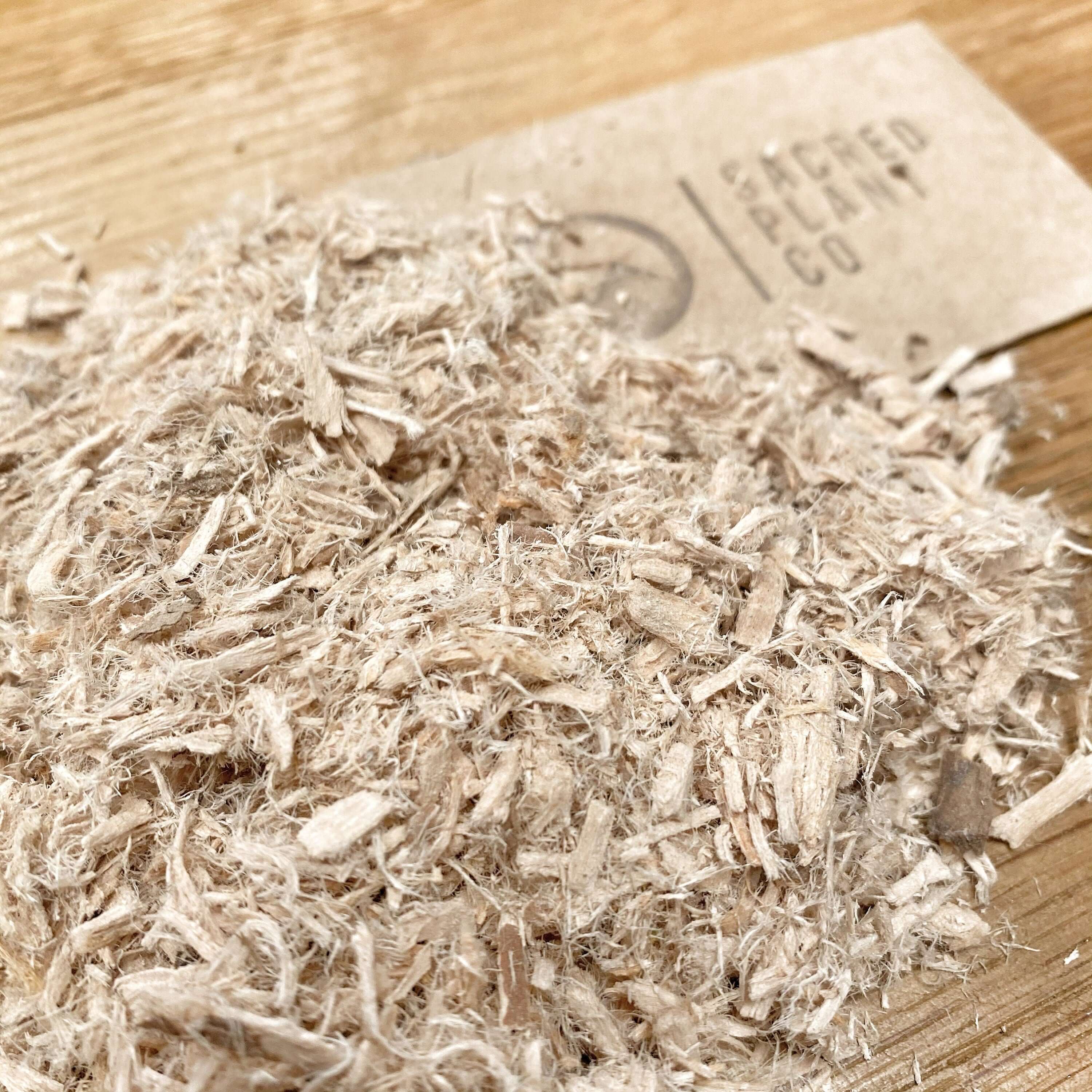 Premium Slippery Elm Bark by Sacred Plant Co, showcasing shredded texture and natural color against a wooden background.