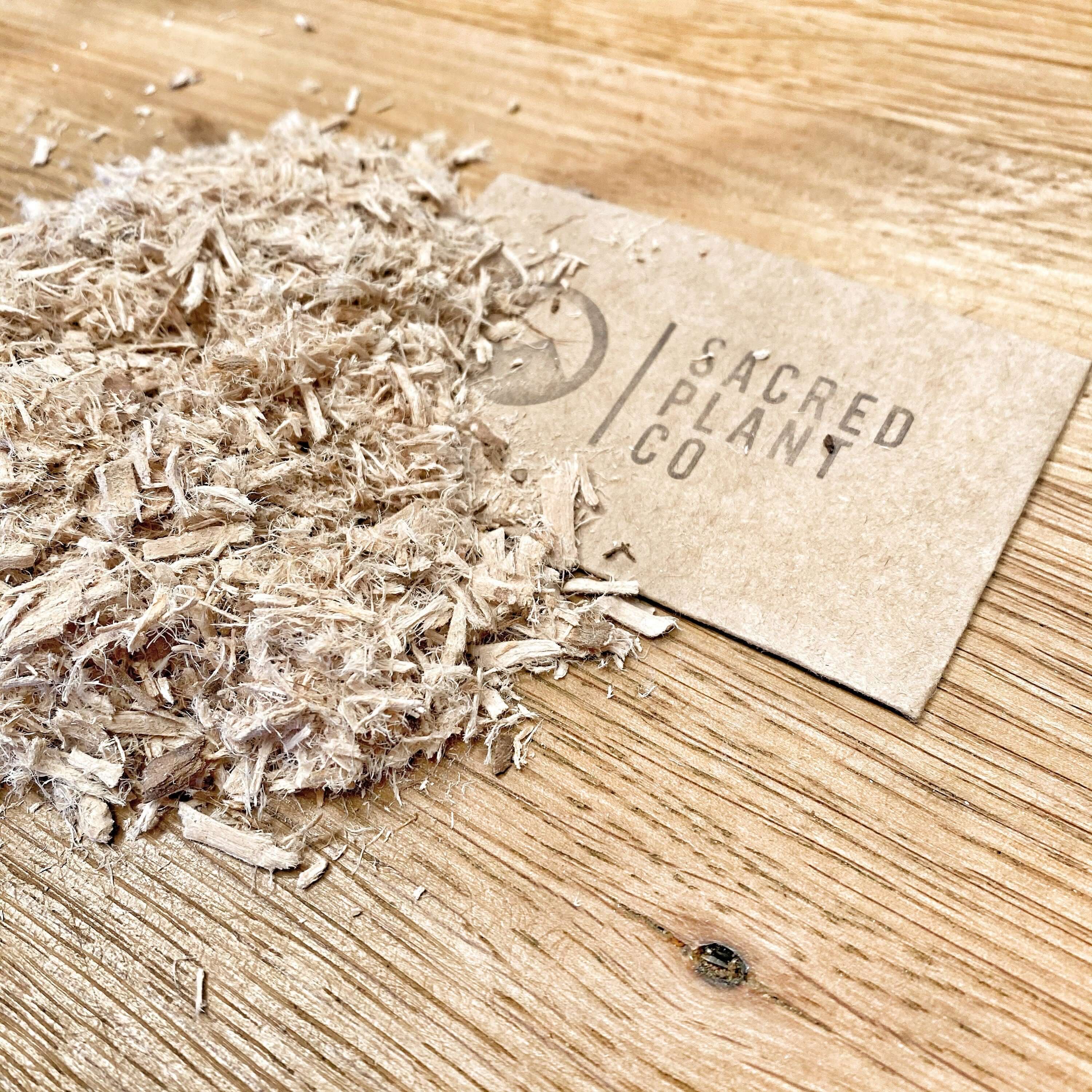 Close-up of shredded Slippery Elm Bark by Sacred Plant Co, premium quality, beige tones on a rustic wood background.