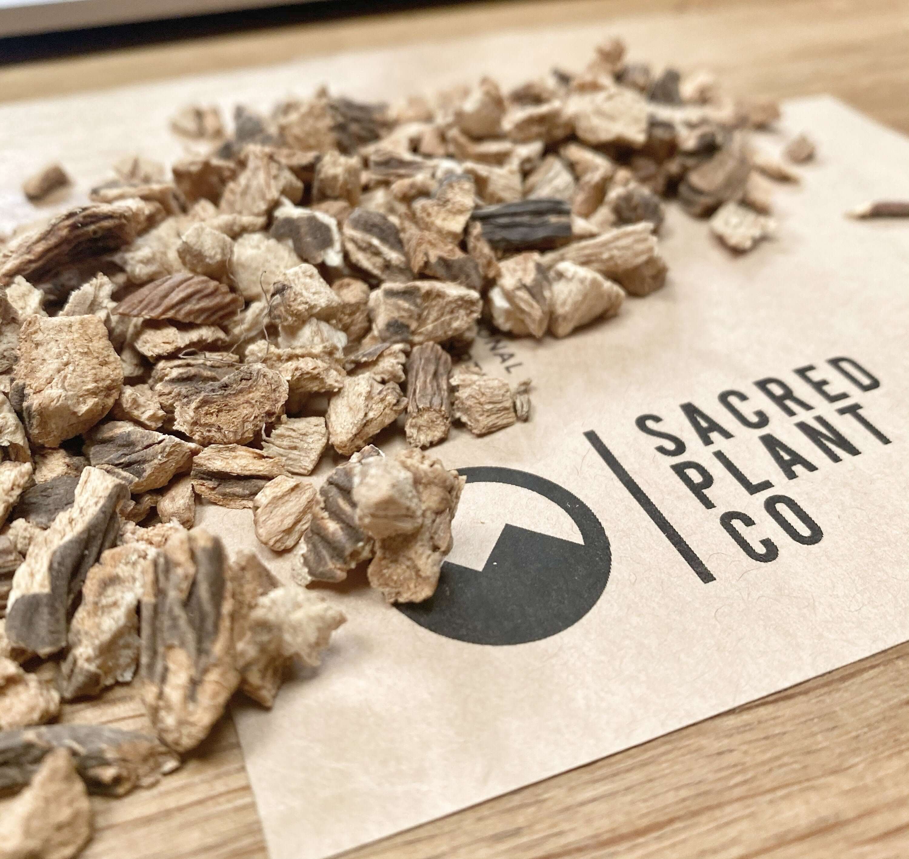 Organic Gentian Root pieces, close-up angle emphasizing rough texture, earthy color, and on top of Sacred Plant Co&