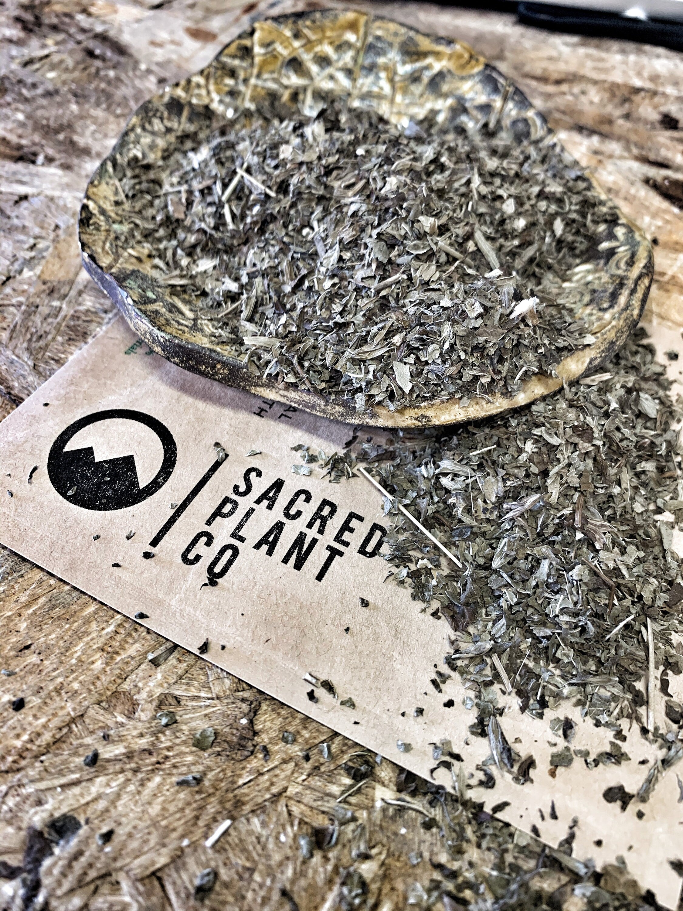 Aromatic dried lemon balm in a natural wooden dish, set on a Sacred Plant Co logo card, emphasizing the herbal freshness and sustainable packaging.