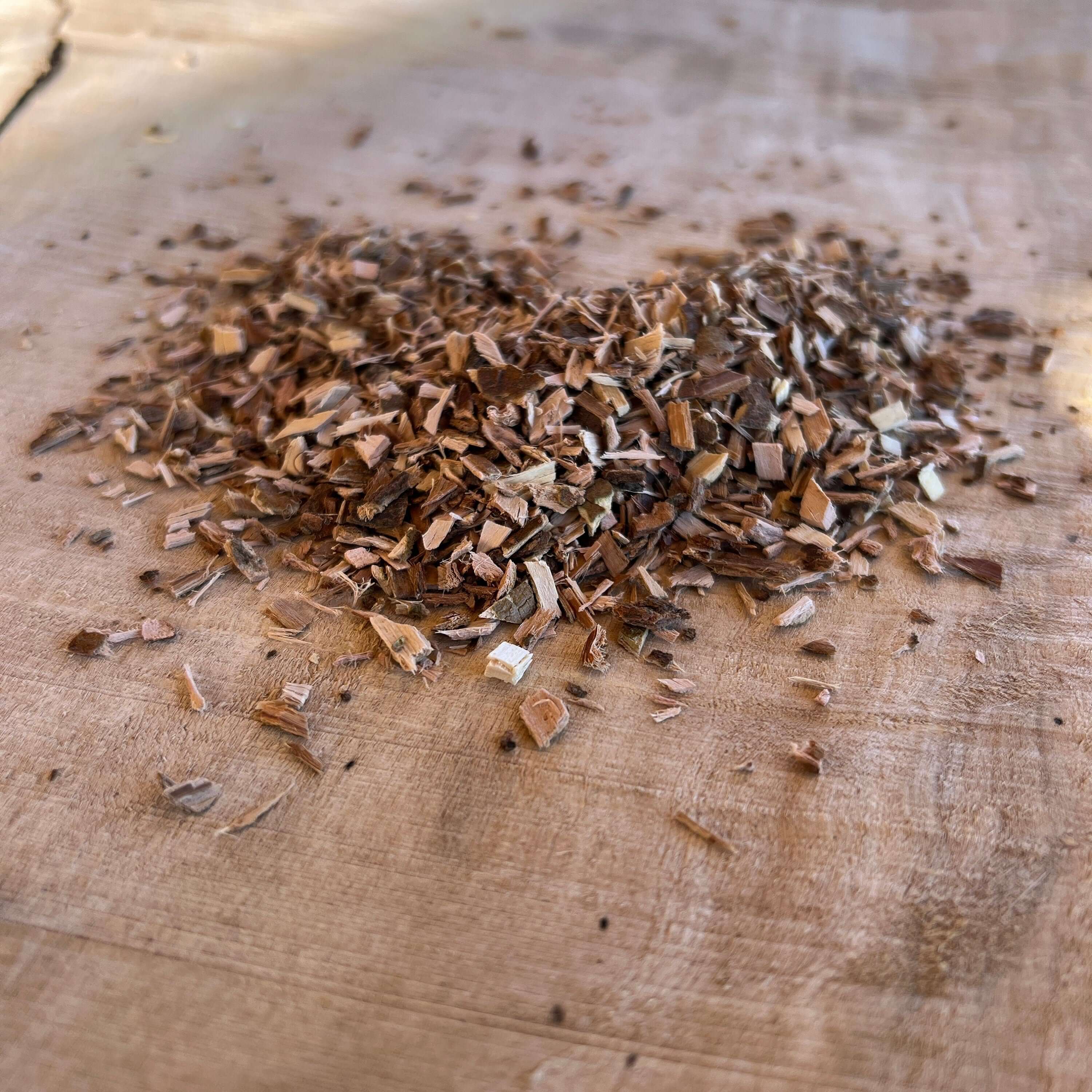 White Willow Bark from Sacred Plant Co, Small, premium extracted Bark scattered on a rustic wooden surface showcasing its natural texture on wood.