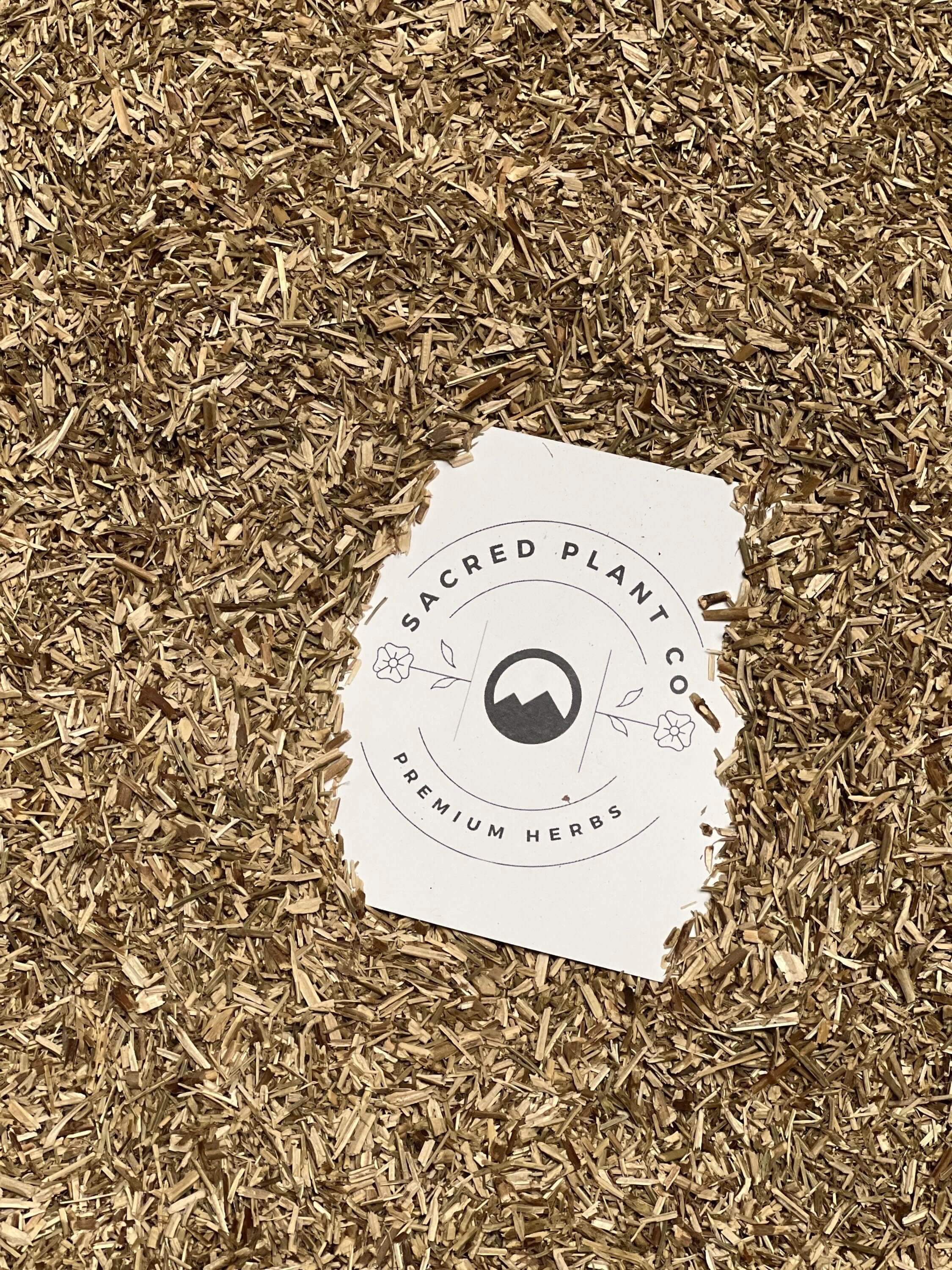 Premium, coarse-textured Hyssop Herb from Sacred Plant Co, golden-brown in color, set against a neutral beige background, highlighting its superior quality and health properties.