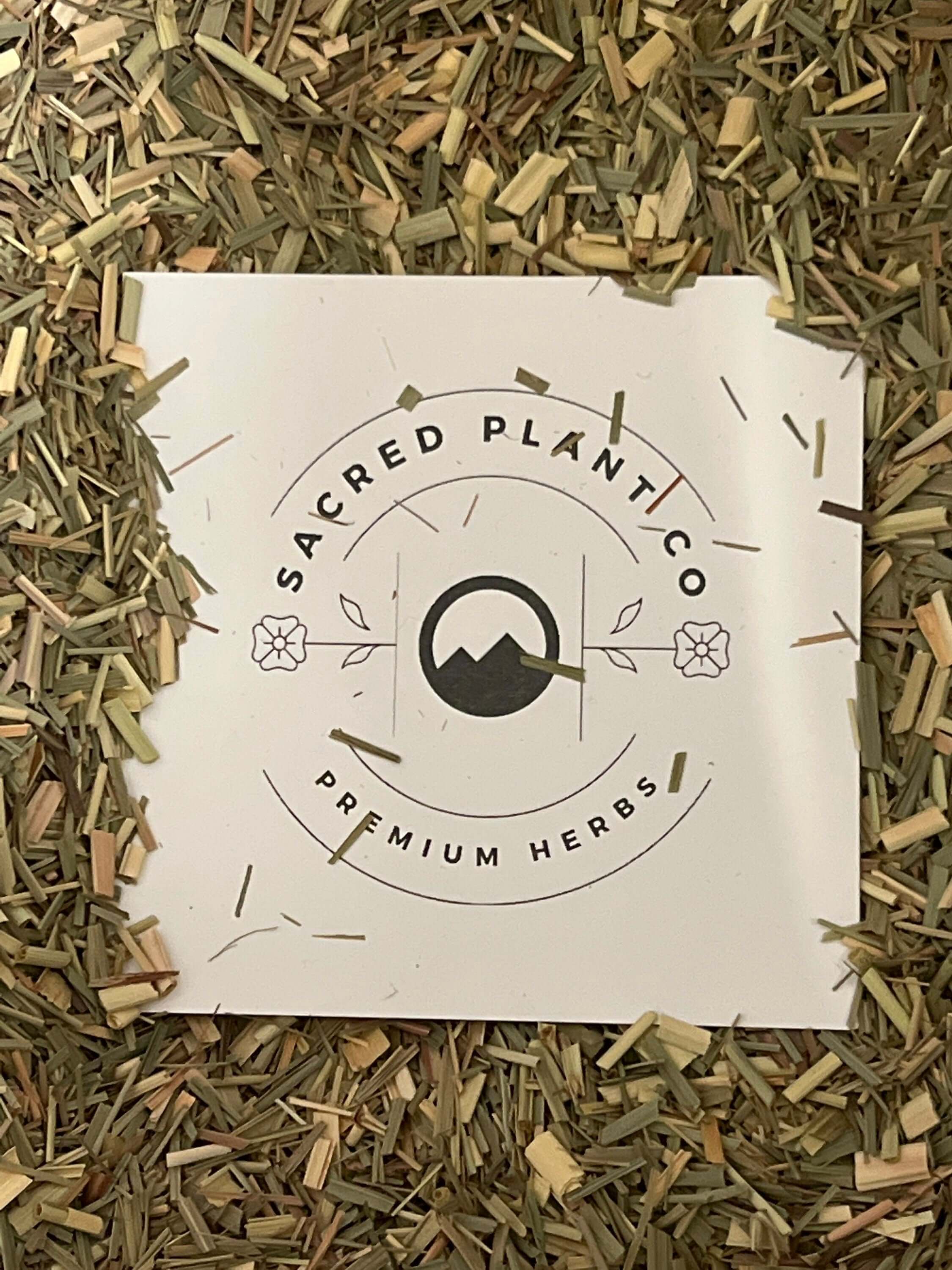 Sacred Plant Co’s premium Lemongrass herb, finely chopped with green and beige tones, spread around branded packaging.