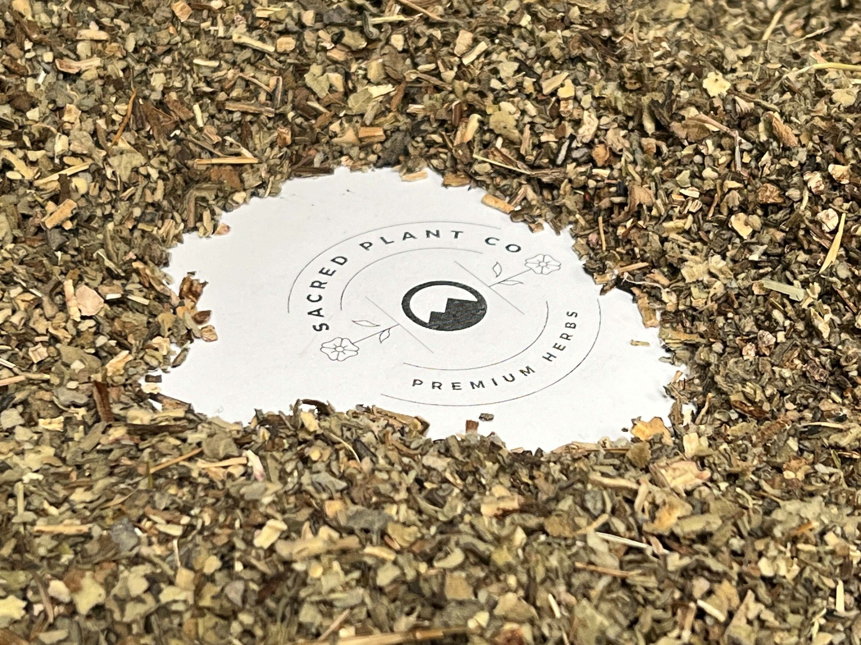 Close-up of shredded Mullein Leaf herbs in muted green and brown shades, surrounding Sacred Plant Co logo to emphasize high-quality natural products.