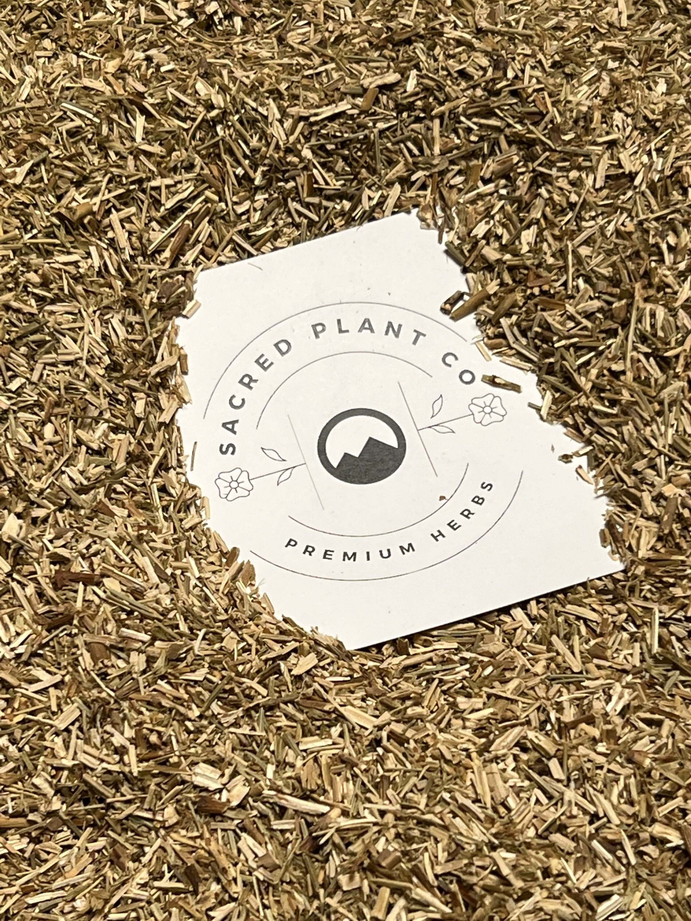 Finely shredded Hyssop Herb in earthy tones from Sacred Plant Co, displaying a rough texture against a beige background, known for its high quality and wellness uses.