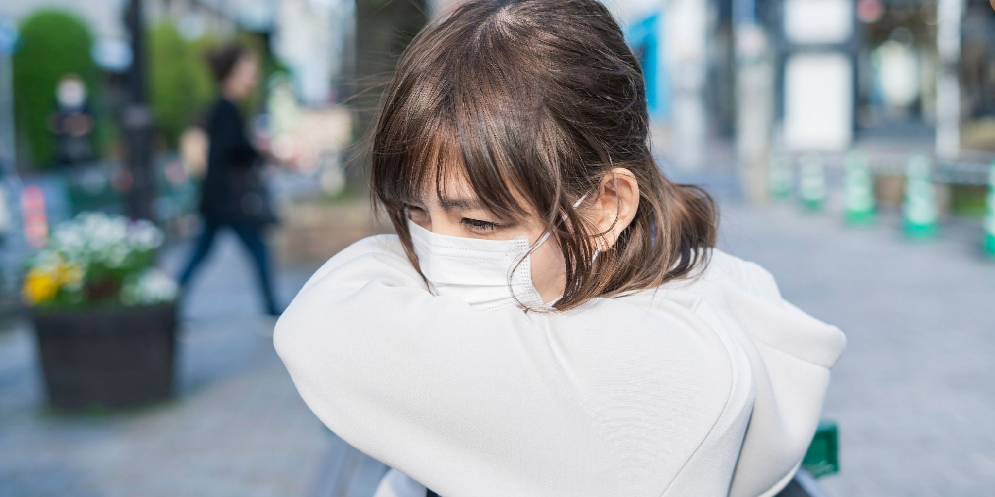 This image of a person wearing a mask while coughing into their arm effectively conveys the concept of health and respiratory wellness.