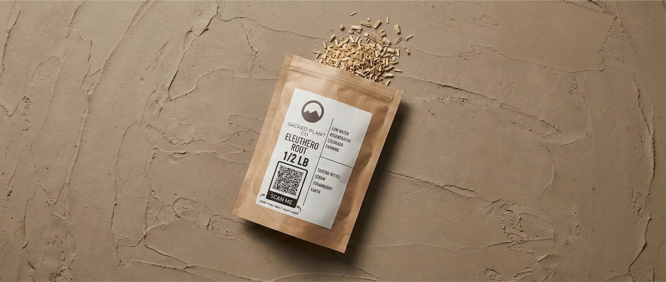 Sacred Plant Co 1/2 lb bag of bulk Eleuthero root lying on textured earth, with dried woody root pieces spilling out.