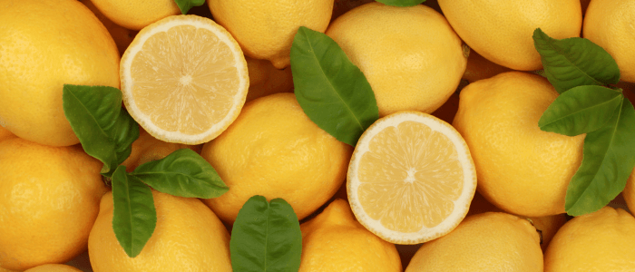 Stack of lemons, single lemon open ready to be peeled. Hero image. 