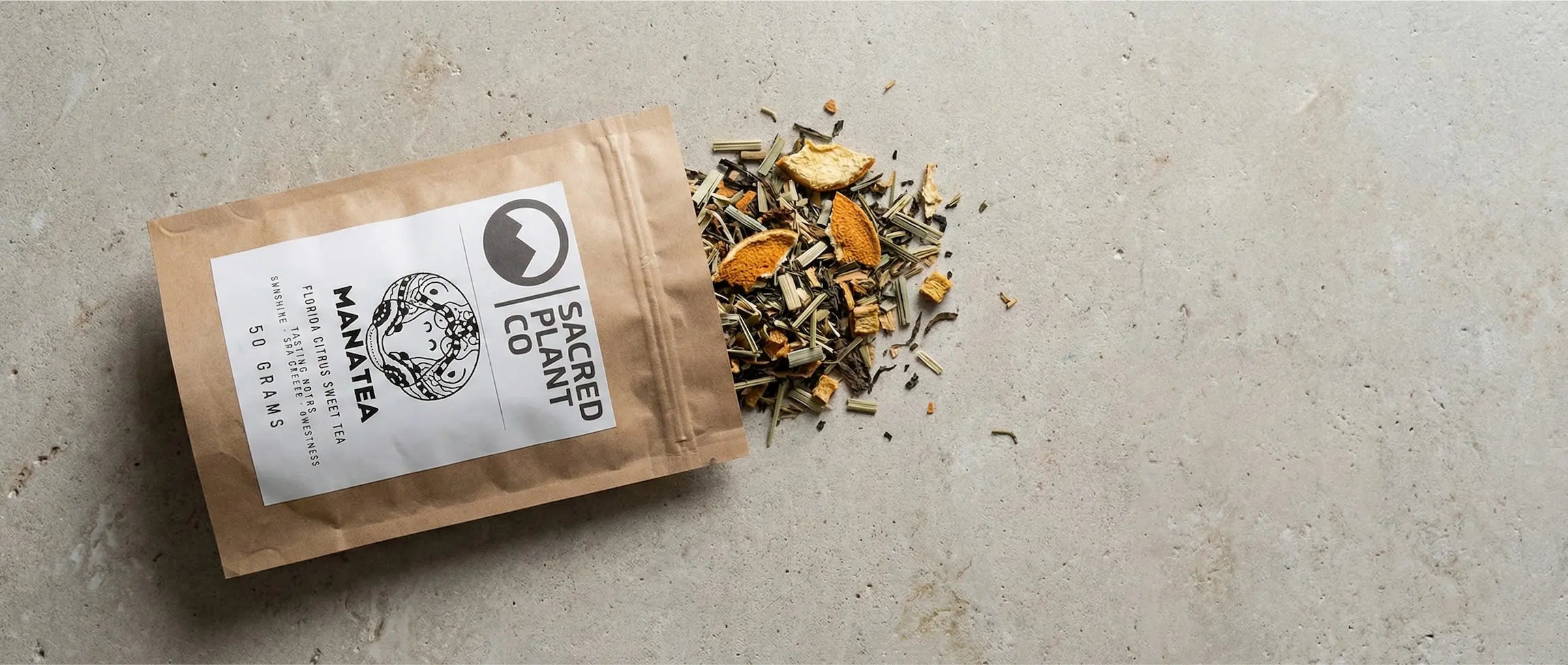 Overhead view of Manatea ingredients including Nektaro black tea leaves, dried citrus peel, and lemongrass on a stone surface.