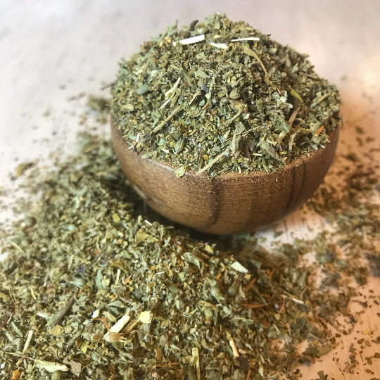 Wooden bowl on a stone countertop with dried, cut, and sifted Damiana, focusing on the herb's preparation for herbal use.