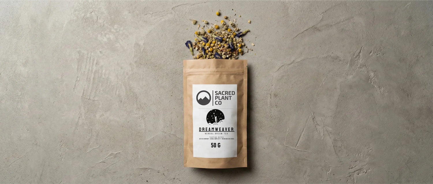 Top-down flatlay of Sacred Plant Co's Dreamweaver Herbal Dream Tea pouch on a textured concrete surface, with loose leaf chamomile, blue lotus, and Calea zacatechichi herbs spilling artfully from the top.