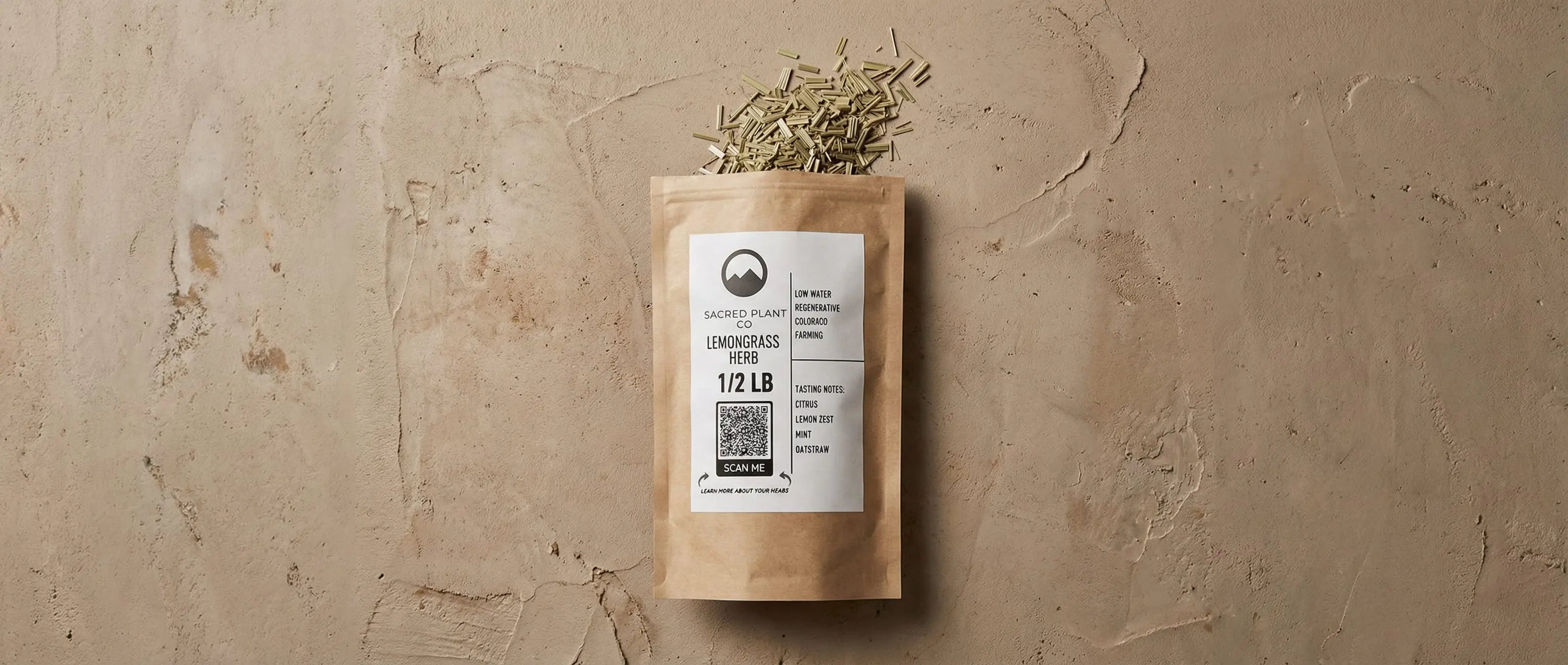 Dried, cut, and sifted lemongrass stalks spilling out of the top of a Sacred Plant Co package, showing the coarse texture and green-yellow color of the herb.