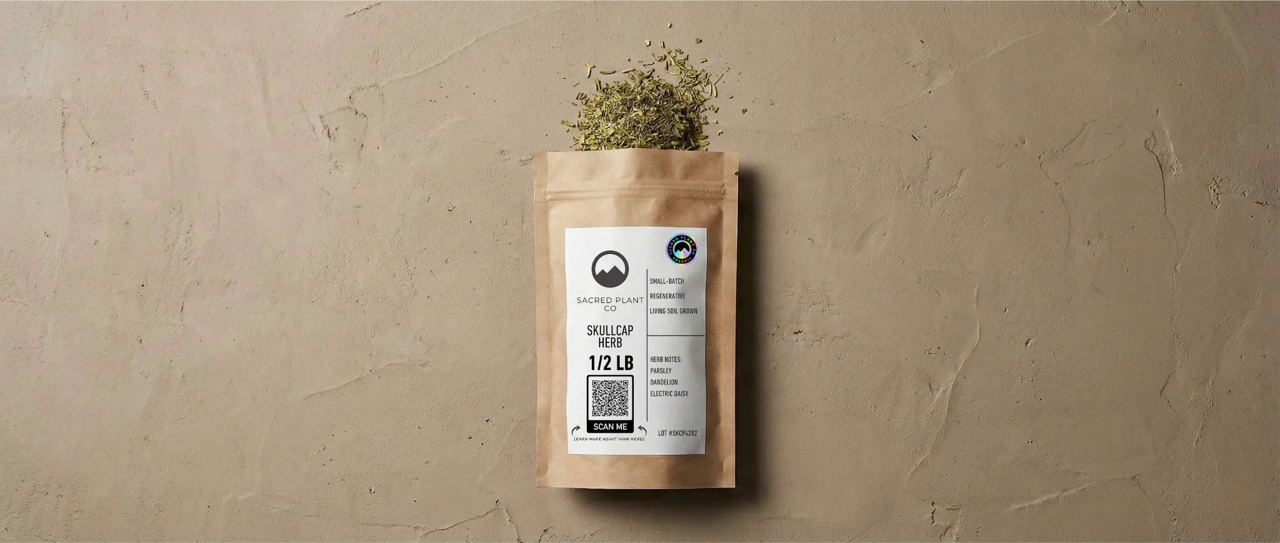 Eco-friendly kraft paper pouch of dried Skullcap herb laying on a textured stone surface, with vibrant green dried leaves spilling from the top, demonstrating proper drying and storage color.