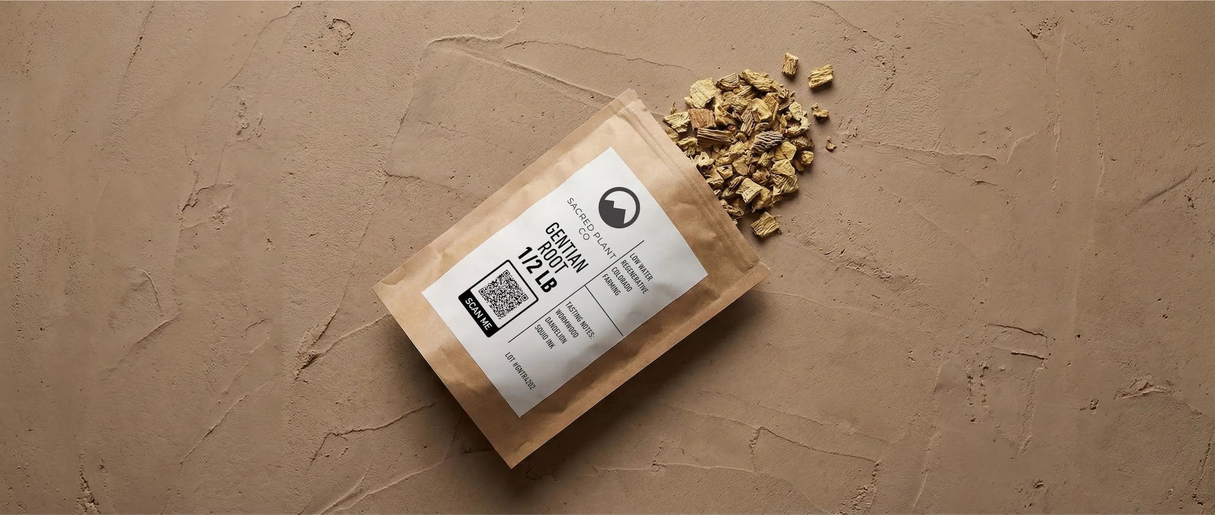 Sacred Plant Co Gentian Root package spilled open to reveal dried, chopped root pieces on a textured beige surface.