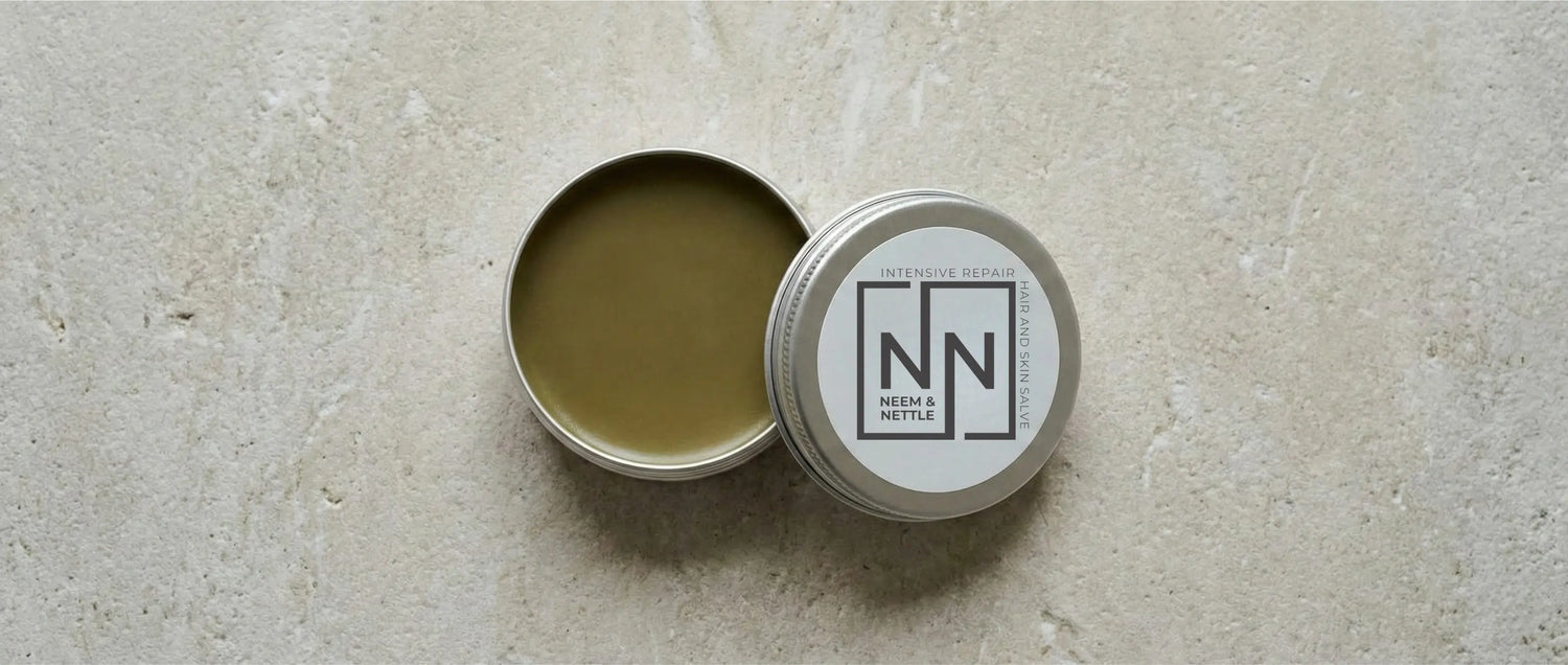 Open tin of deep green Neem & Nettle salve, rich in antimicrobial azadirachtin for soothing psoriatic plaques and restoring the skin barrier.