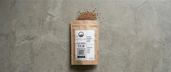 Sacred Plant Co half-pound bag of flax seeds on a concrete surface, displaying the "Scan Me" QR code and tasting notes.