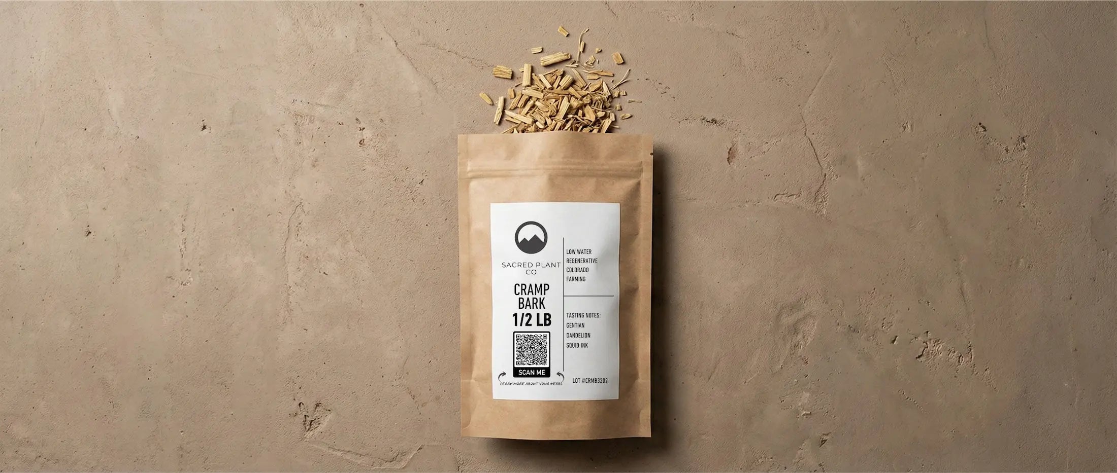 Dried cramp bark strips spilling from a labeled Sacred Plant Co kraft paper pouch onto a stone surface, showing the bark's fibrous texture and medium-brown color.