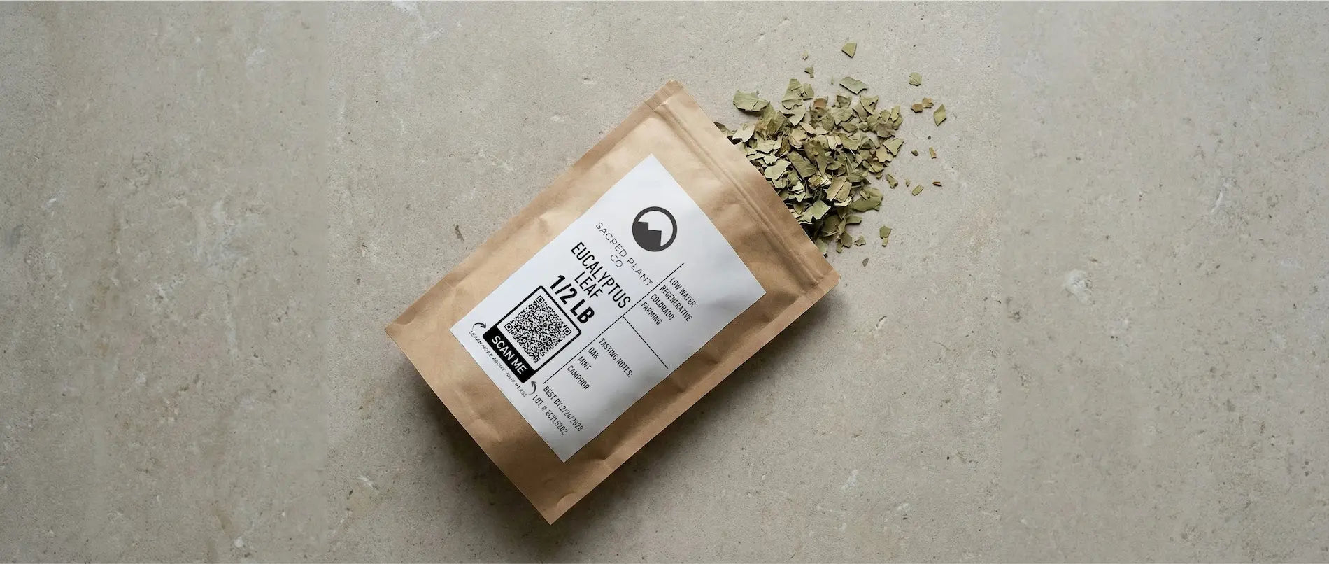 Top-down editorial view of a Sacred Plant Co Eucalyptus Leaf package resting on a textured stone surface. Premium dried cut-and-sifted eucalyptus leaves—traditionally used for respiratory health and congestion relief, spill naturally from the open bag.