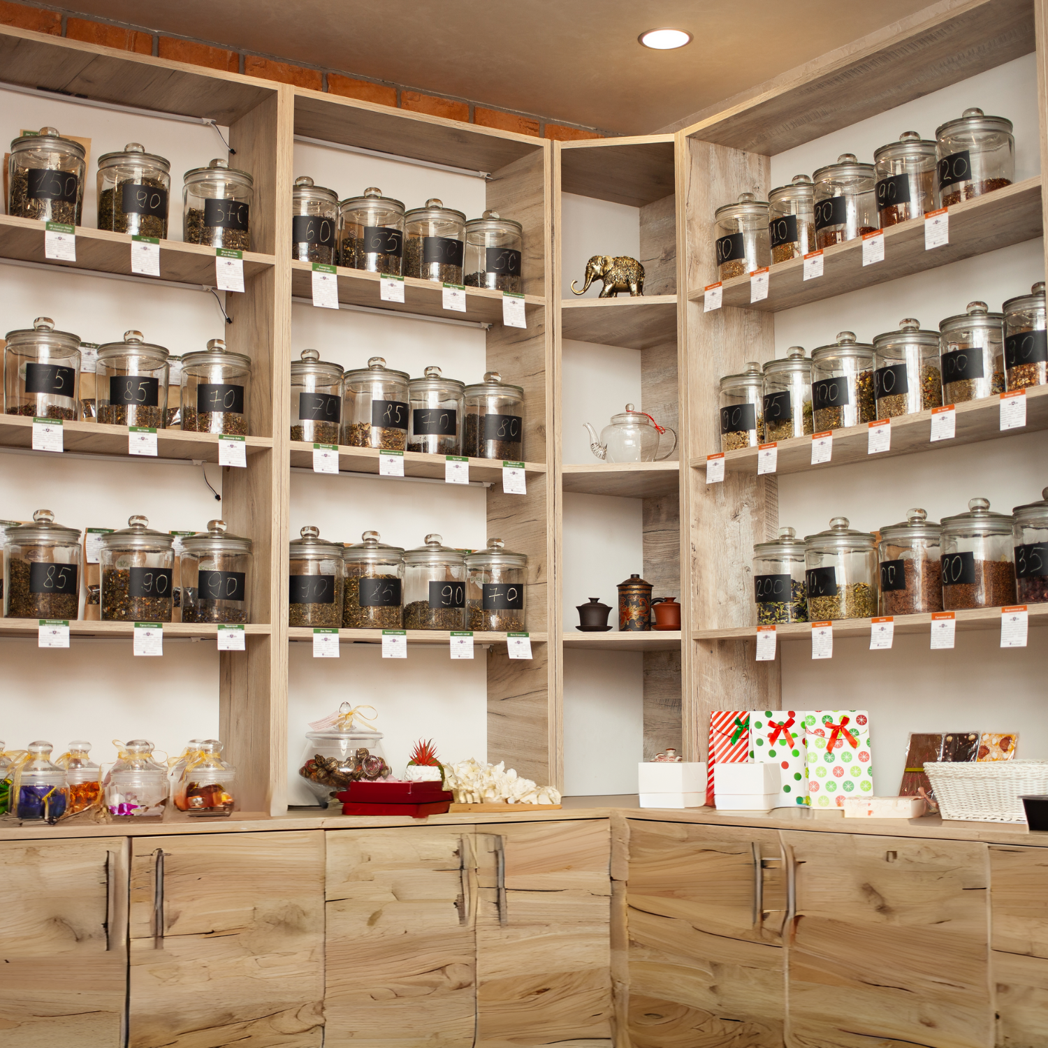 A cozy tea shop interior with natural wood shelves filled with clear glass jars of various loose leaf teas. The shelves are well-stocked with Sacred Plant Co Wholesale Tea, reflecting a warm and inviting ambiance.