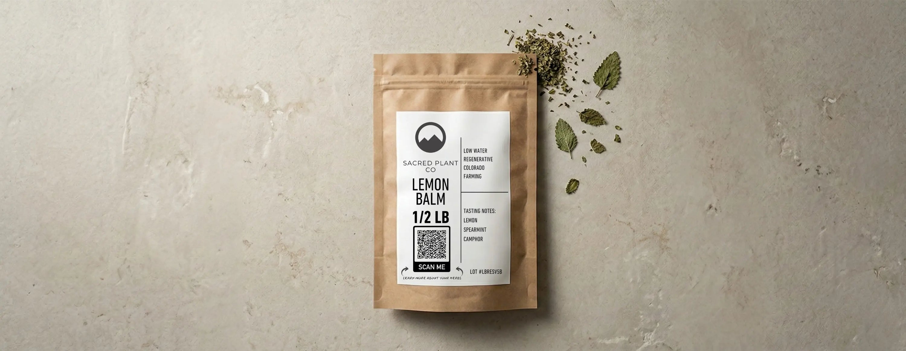 A flat lay editorial photograph of a Sacred Plant Co lemon balm herb bag on a honed limestone surface with dried botanicals