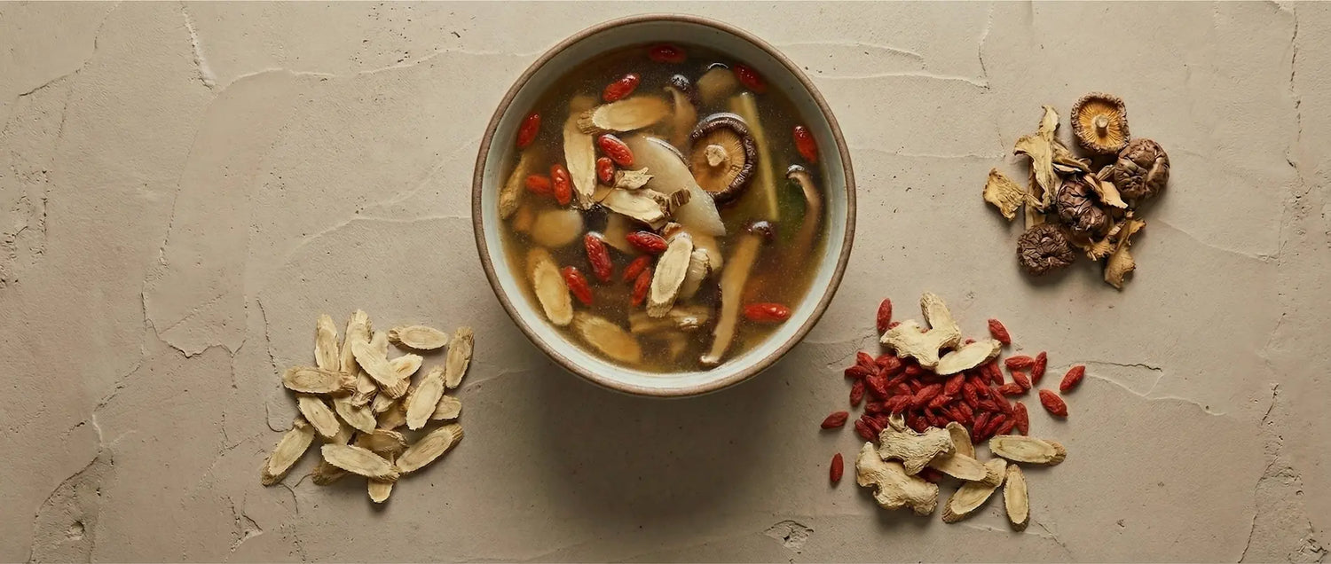 A finished serving of vegetarian TCM healing soup, showcasing the golden broth color and rehydrated medicinal herbs used to strengthen Wei Qi.