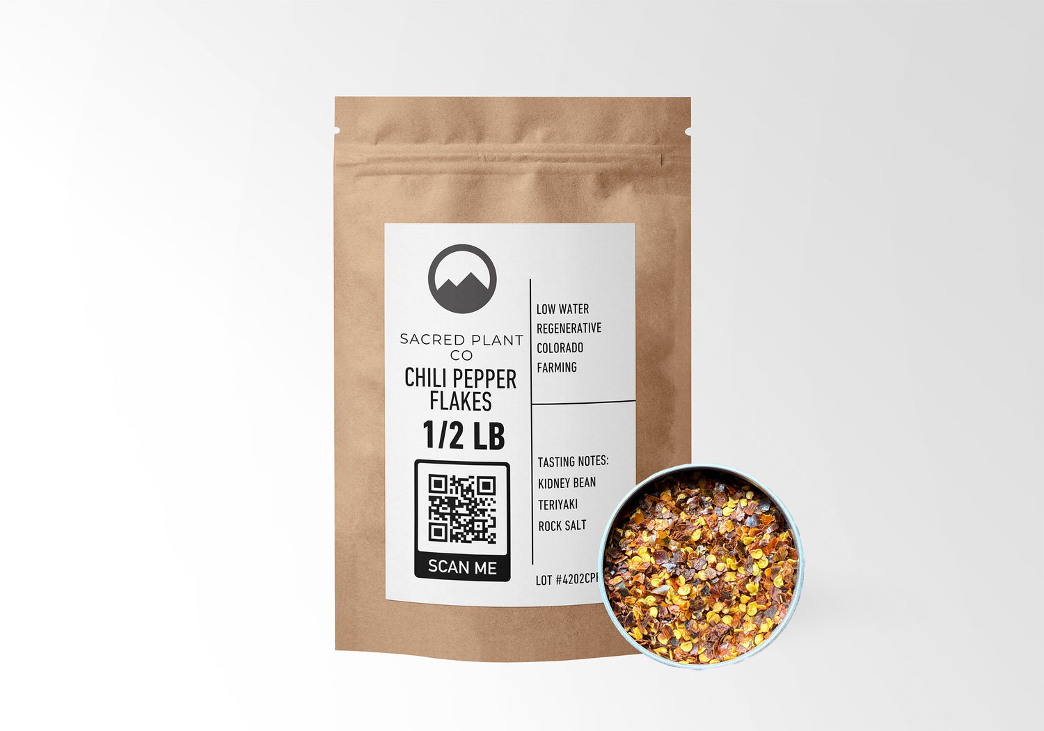 Sacred Plant Co Chili Pepper Flakes 1/2 LB in eco-friendly kraft paper packaging, with a sample in a silver tin. Used for adding spice to dishes, enhancing metabolism, and supporting digestion.