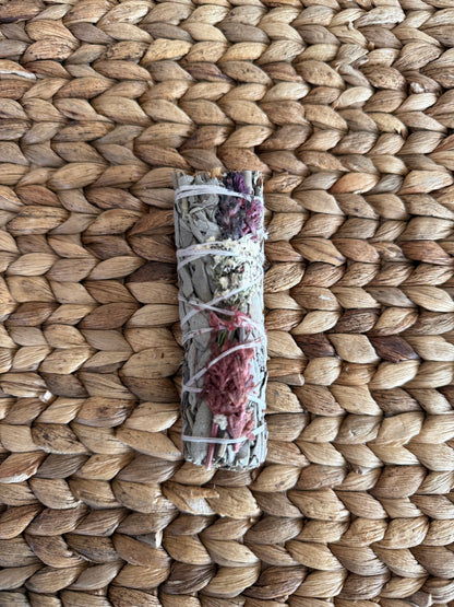 Single consecrated white sage smudge stick with vibrant floral bindings, sustainably harvested and crafted for sacred energy clearing and meditation.