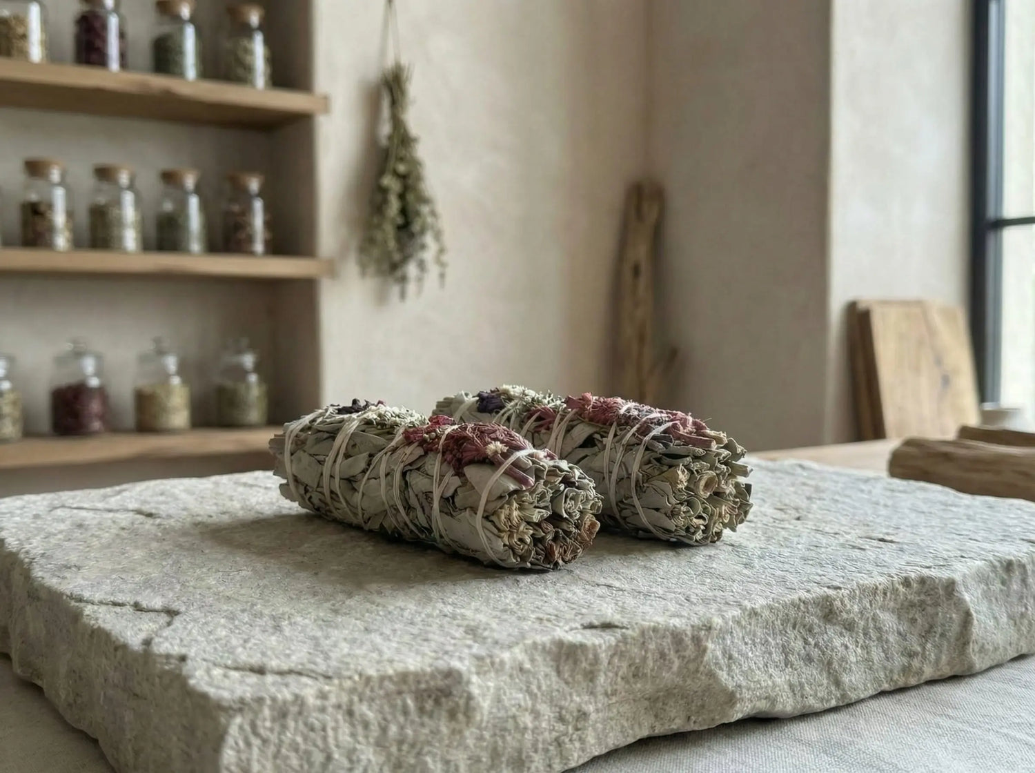 Two consecrated white sage smudge sticks resting on natural stone, showing size and ceremonial quality.