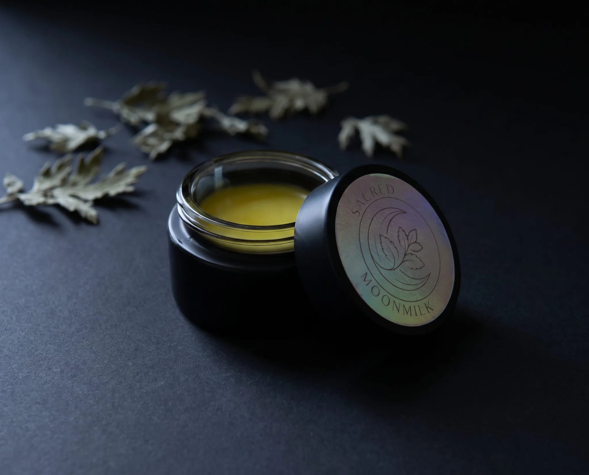 Flat lay of Moonmilk night balm botanicals: mugwort, California poppy, lemon balm, marshmallow, jojoba, beeswax and shea