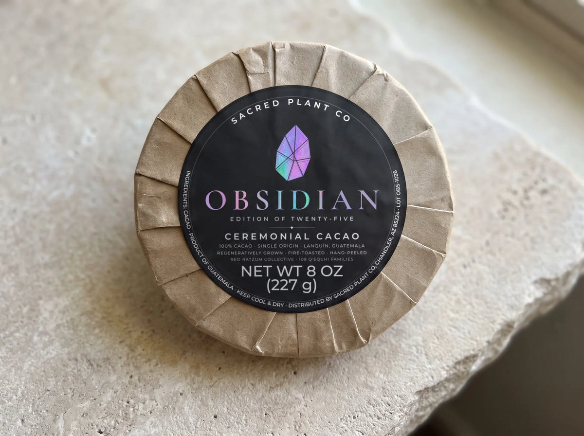 Hand-wrapped 8 oz ceremonial cacao round on a travertine slab, label reading single origin, Lanquín, Guatemala, regeneratively grown