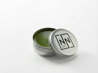 Open tin of Sacred Plant Co Neem &amp; Nettle Salve with the lid leaning against it on a neutral background.