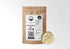 A 1/2 lb kraft pouch of Sacred Plant Co organic, cut Ashwagandha Root (Withania somnifera) displayed next to a sample of the chopped, dried pale root. The packaging label emphasizes low-water regenerative farming and lists earthy tasting notes of soil, wormwood, and forest.